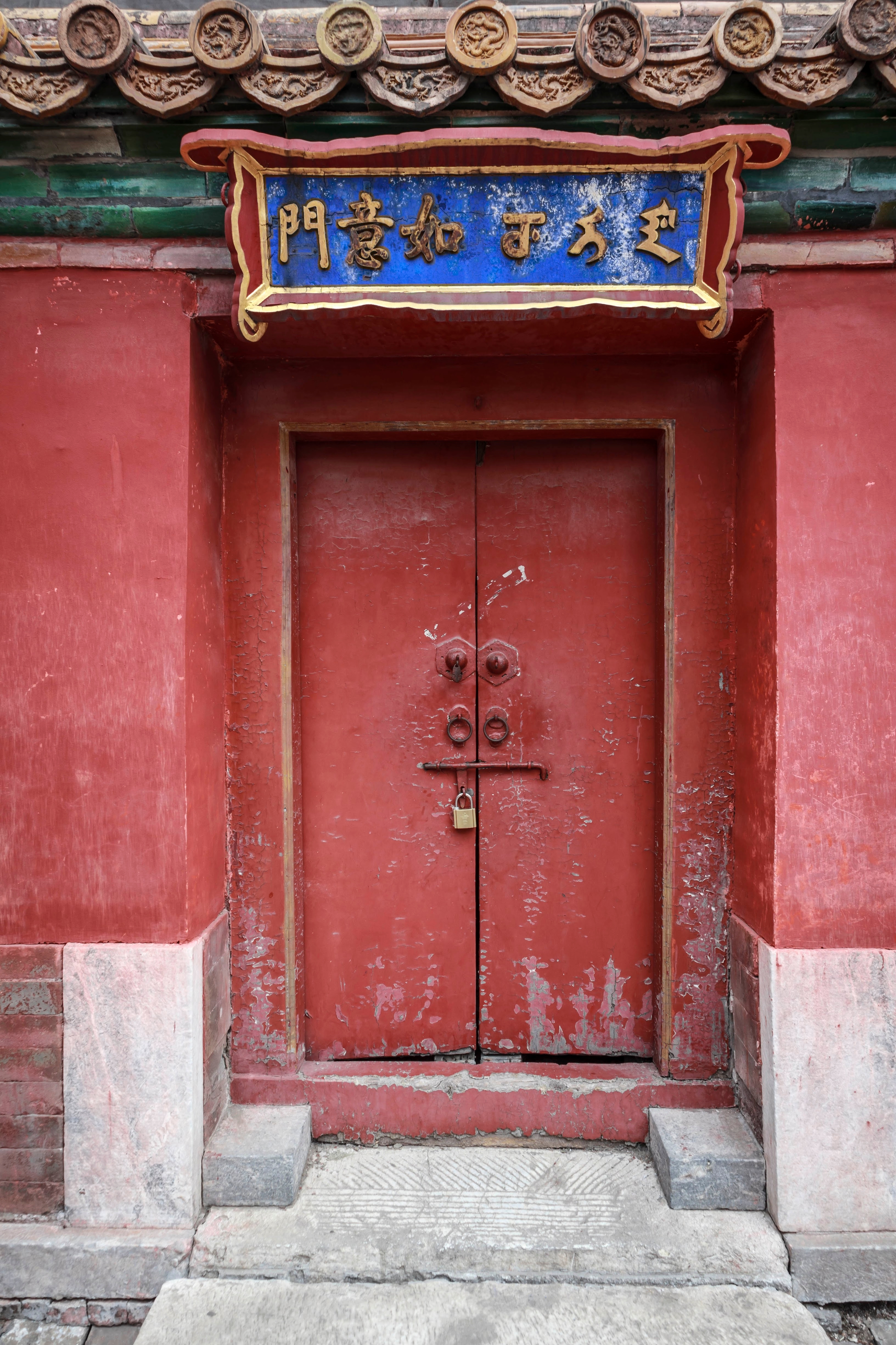 Smuk rød port med gyldent kinesisk skrift ved den historiske Ruyi-port i Den Forbudte By, Beijing