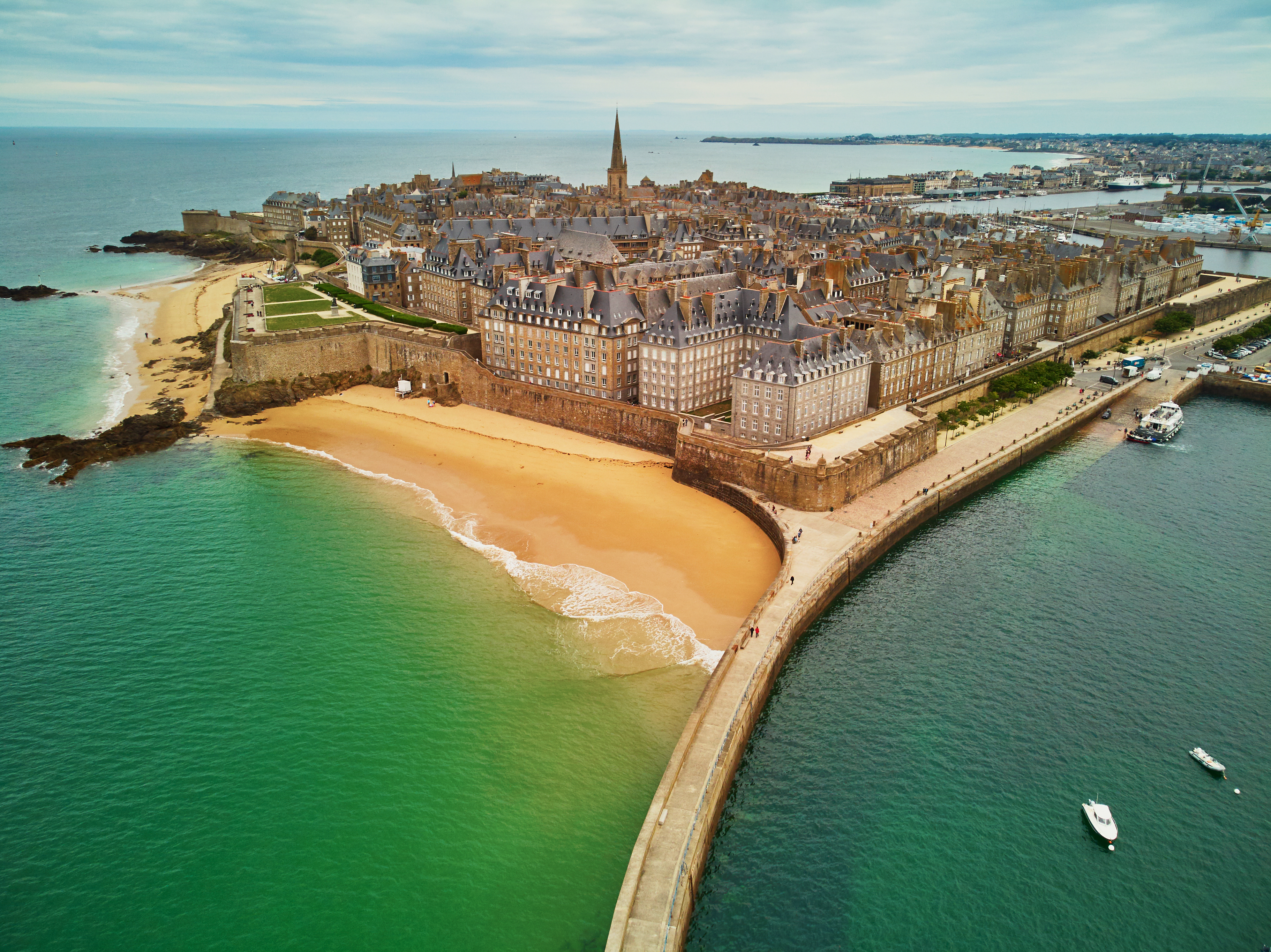 Spektakulært luftbillede af Saint-Malo fæstningsby med gylden sandstrand og krystalklart vand i Bretagne