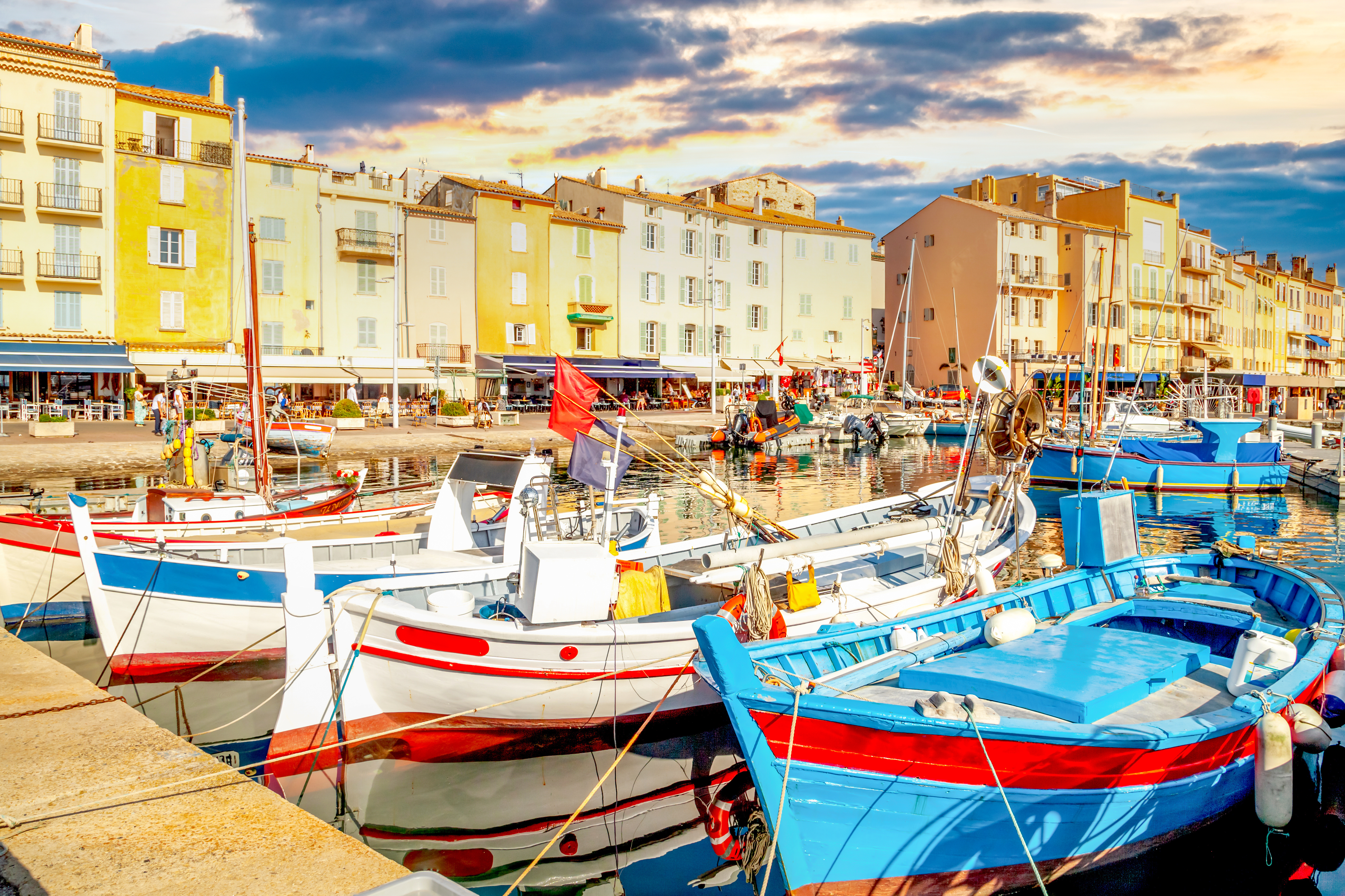 Traditionelle farverige fiskerbåde i Saint-Tropez havn med charmerende kaféer og bygninger langs vandkanten i Sydfrankrig