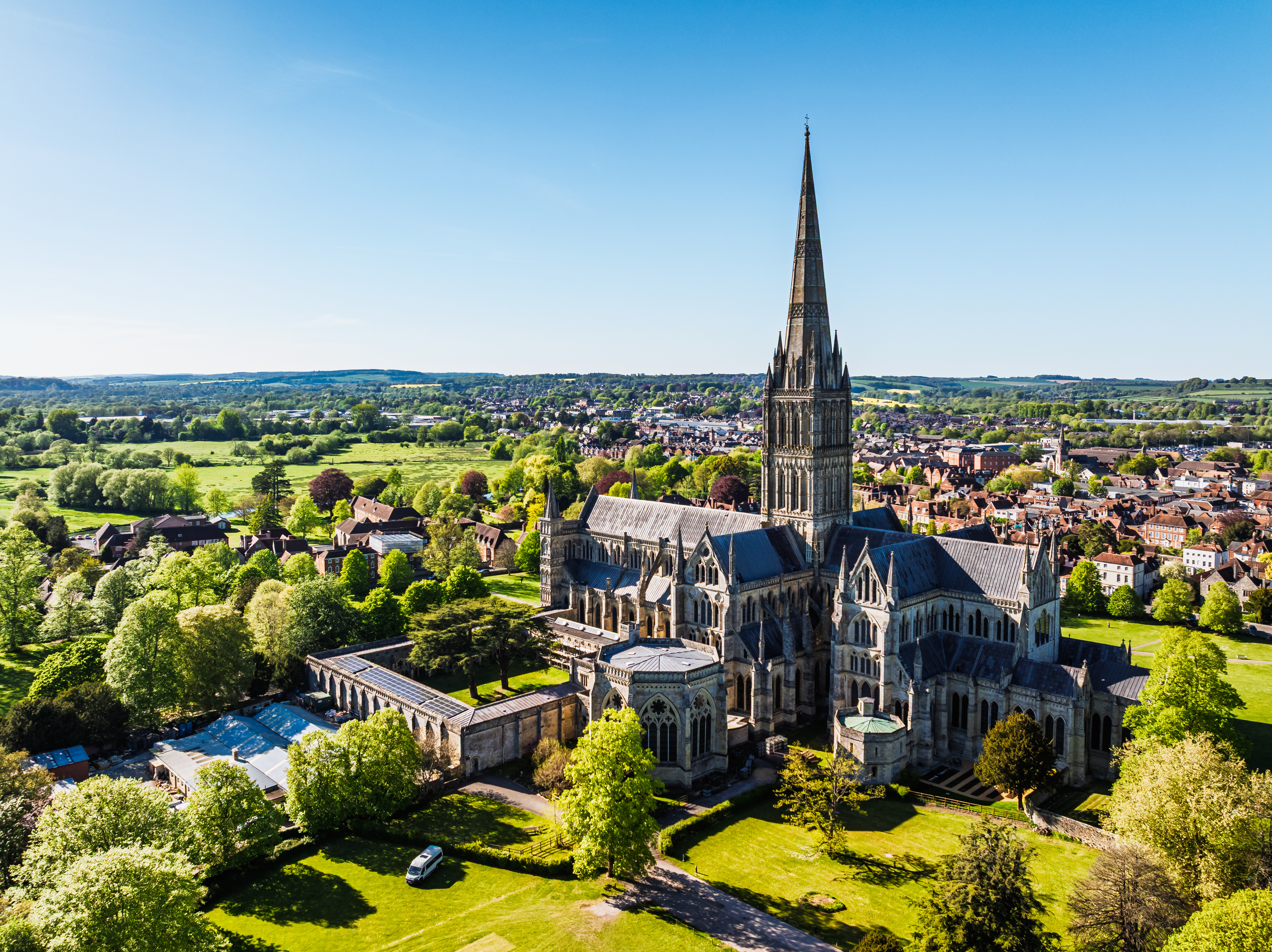 Imponerende luftfoto af Salisbury Cathedral med det høje gotiske tårn og den grønne katedral-plads i hjertet af Salisbury, Wiltshire