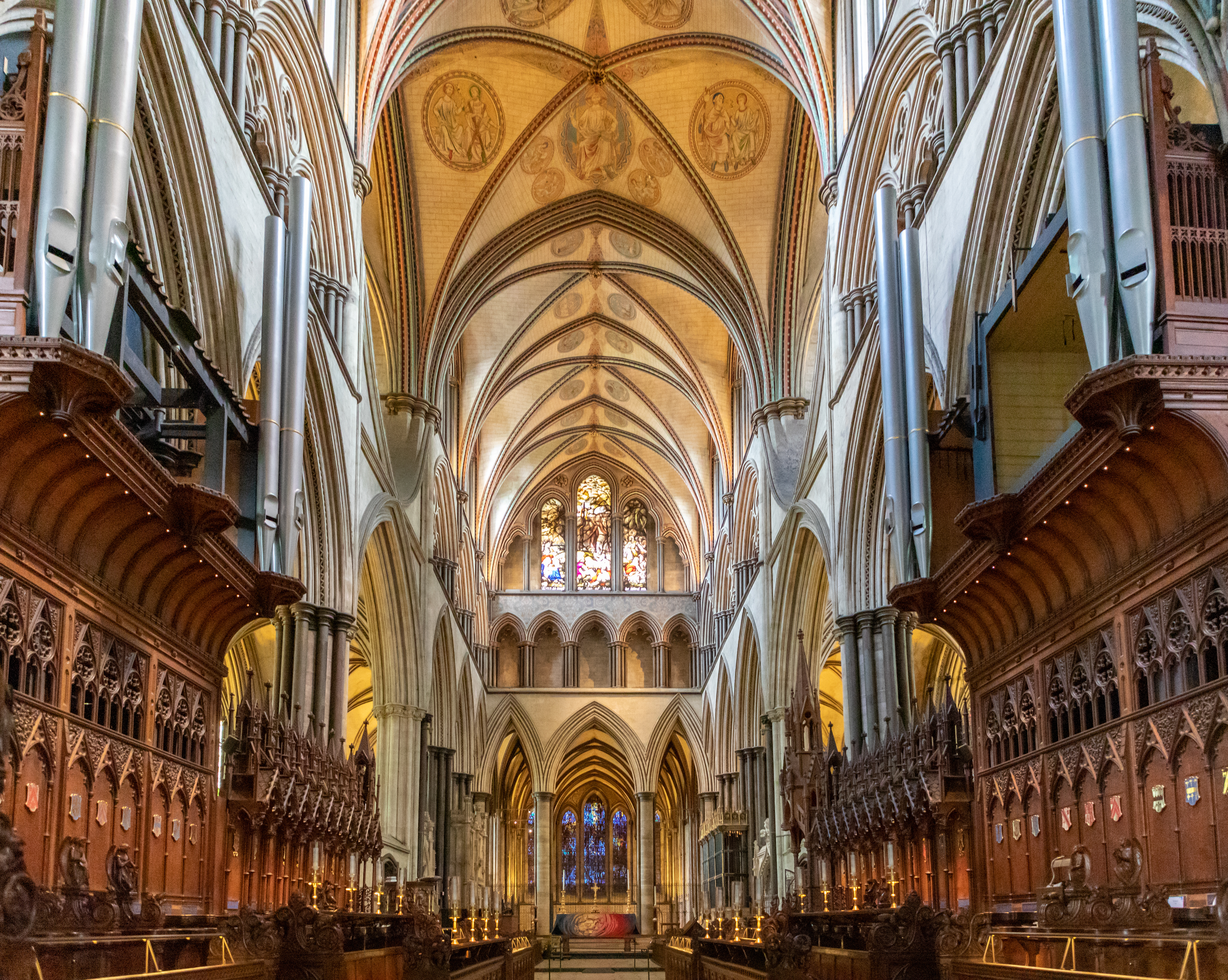 Det storslåede indre af Salisbury Cathedral med gotiske hvælvinger, udskårne træstole og farverige glasmalerier i England