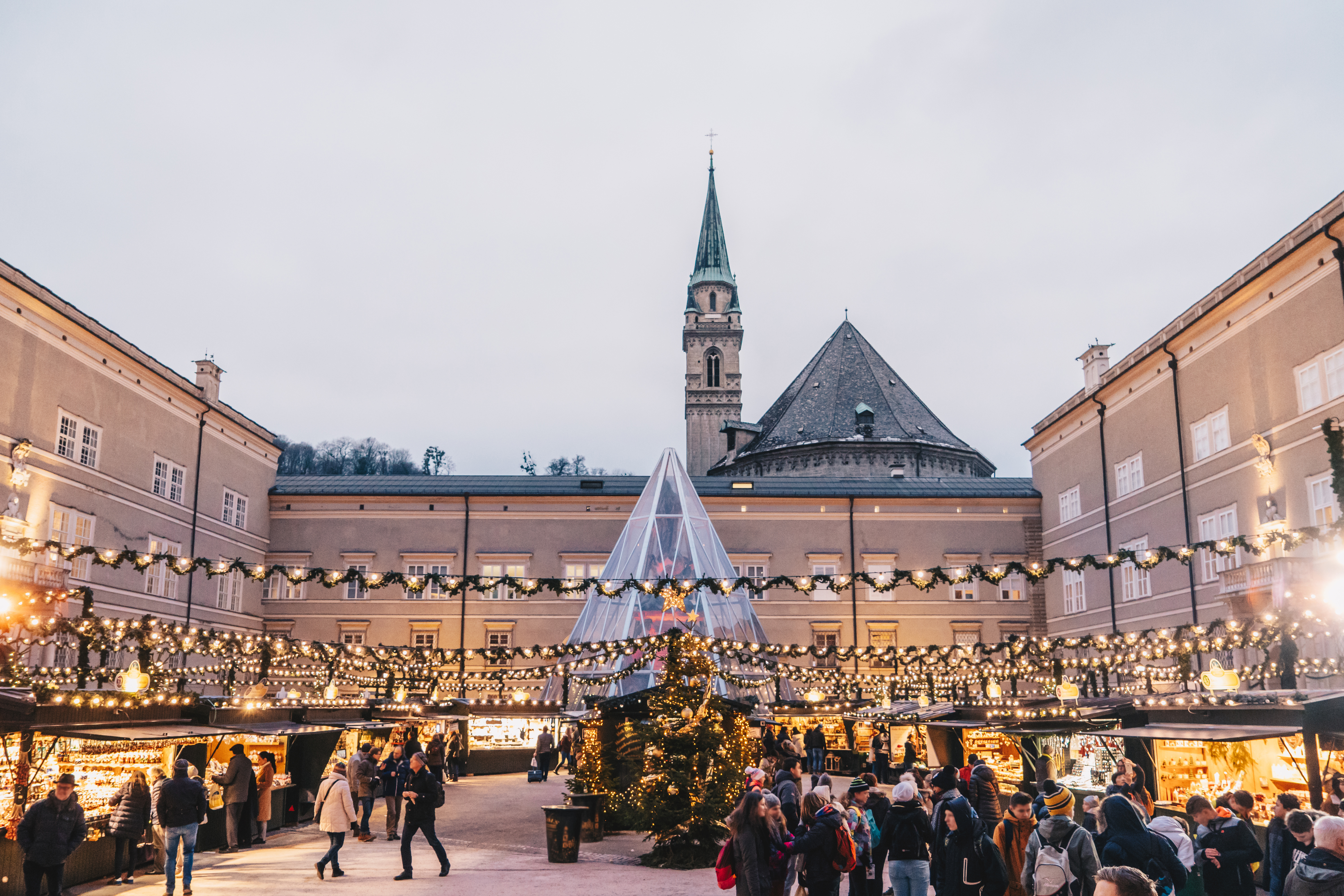 Adventsstemning på julemarkedet i Salzburg med lysdekorationer, juletræer og historiske bygninger på Domplatz