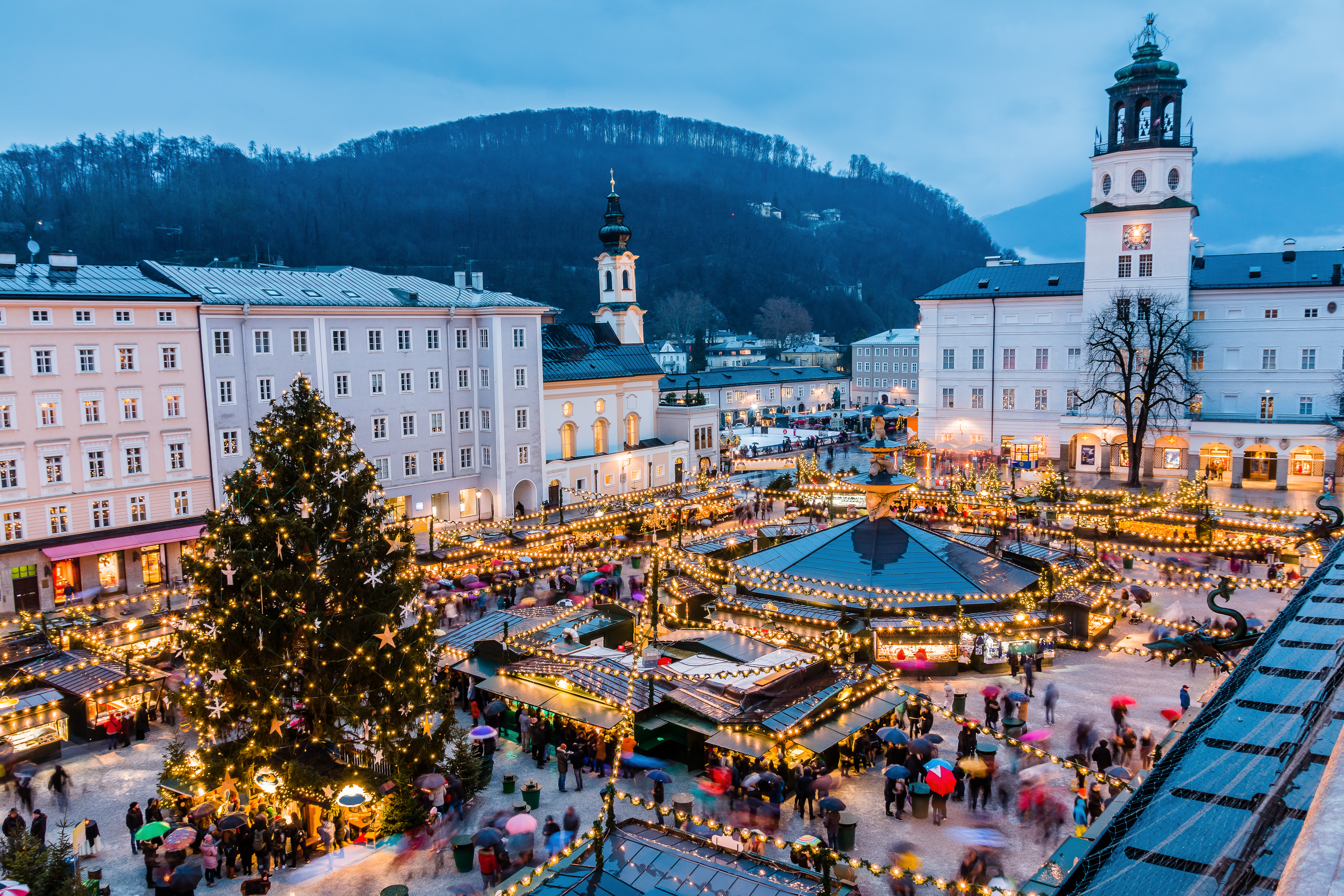 Magisk julemarkeds-atmosfære i Salzburg med oplyste boder, julepynt og den historiske bymidte badet i aftenbelysning