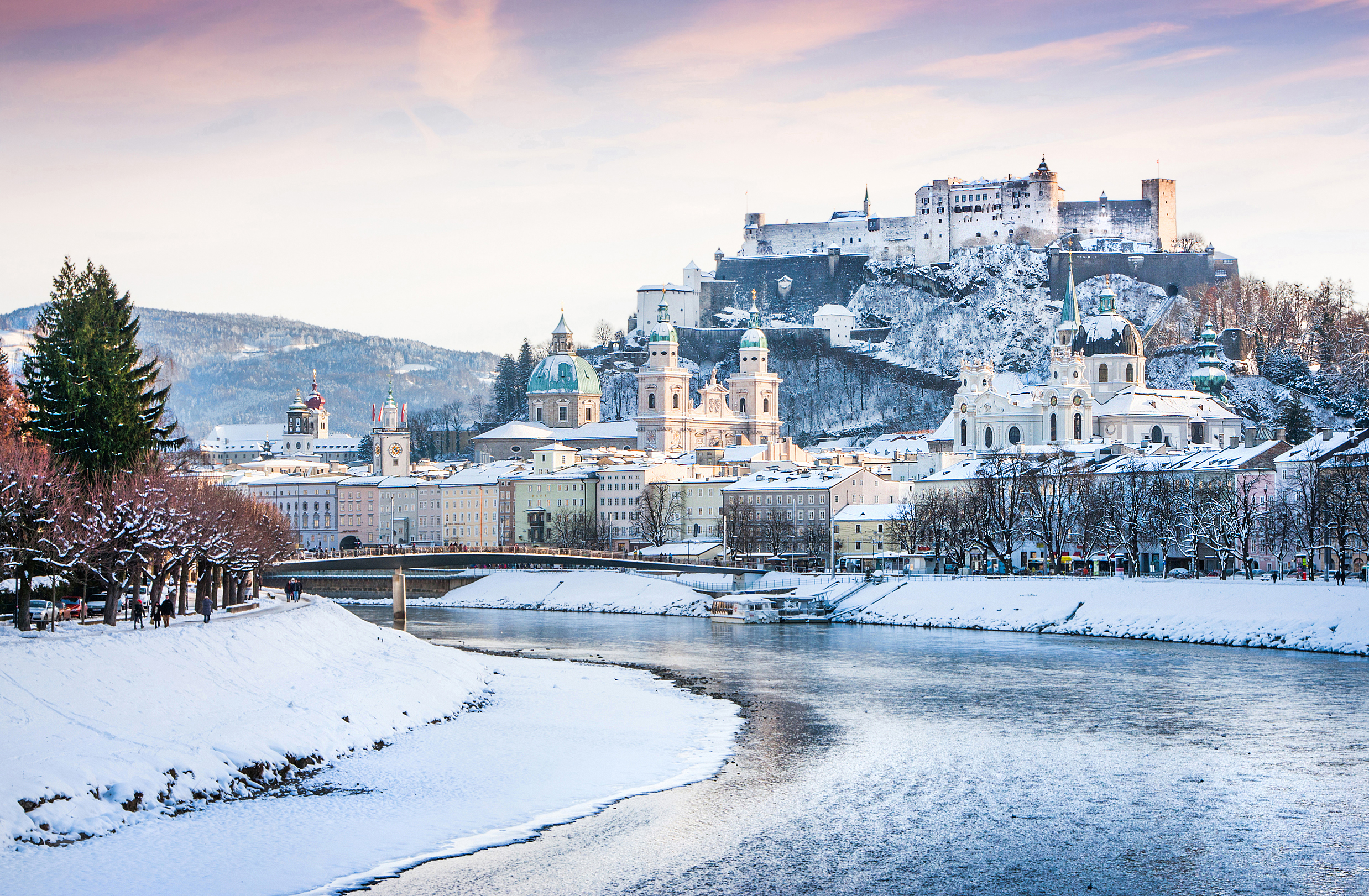 Vinteridyl i Salzburg med den historiske Hohensalzburg-fæstning og Salzach-floden under et snedækket landskab, Østrig