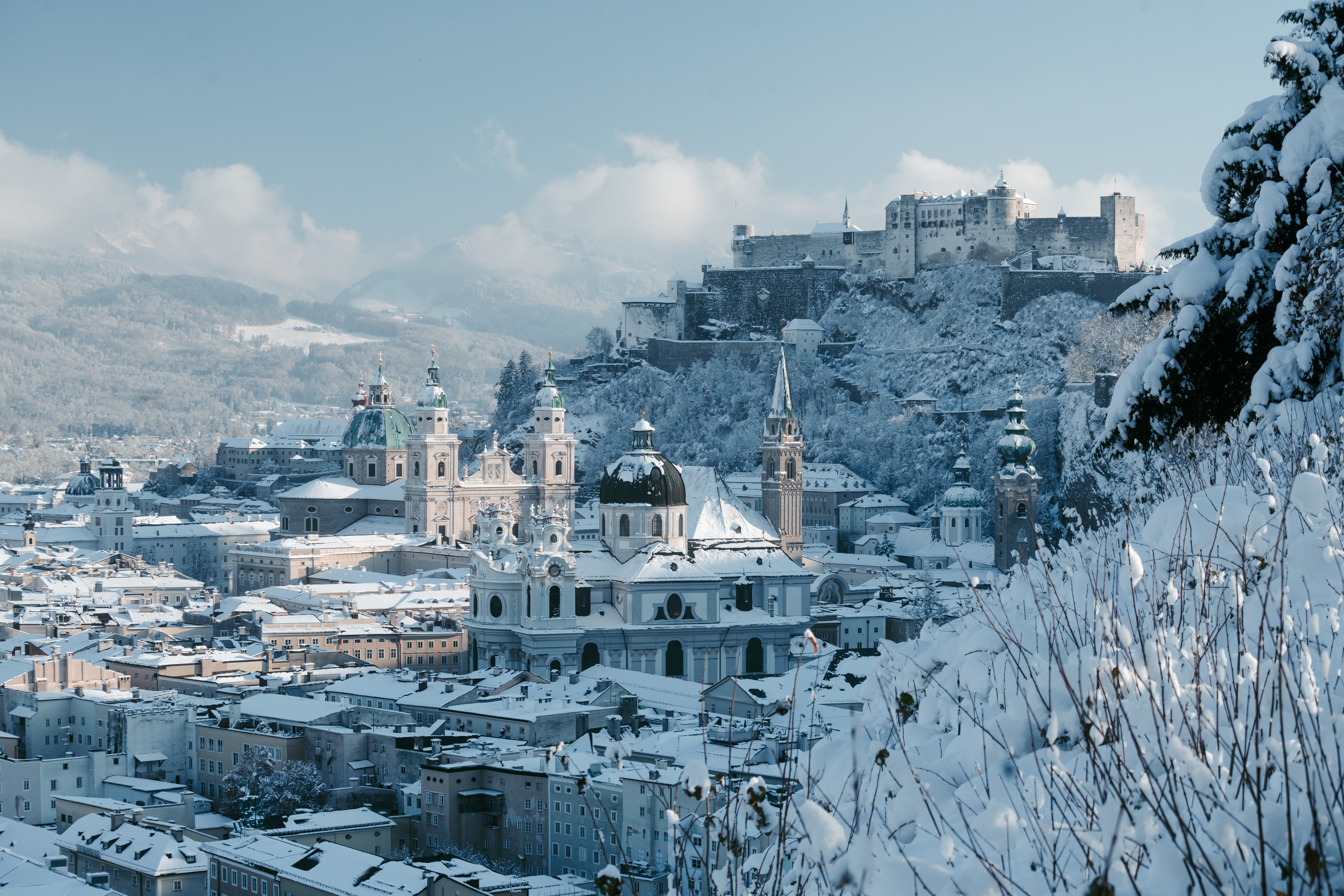 Idyllisk vinterbillede af Salzburg med snedækkede tage, Hohensalzburg-fæstningen og de karakteristiske barokkirker i Salzburger Land