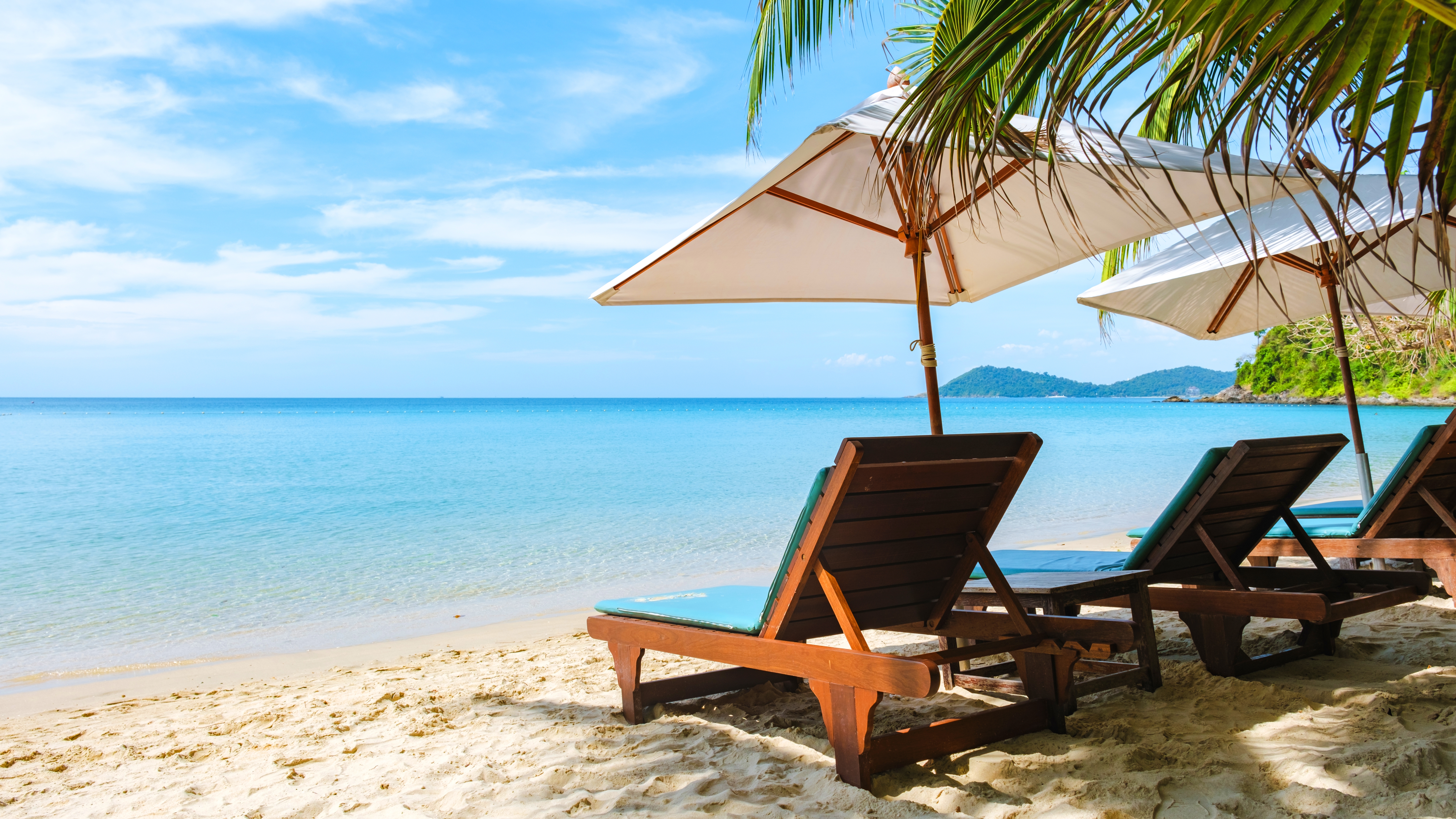 Tropisk strandferie med solsenge og hvide parasoller ved det turkisblå hav på Koh Samet, Thailand