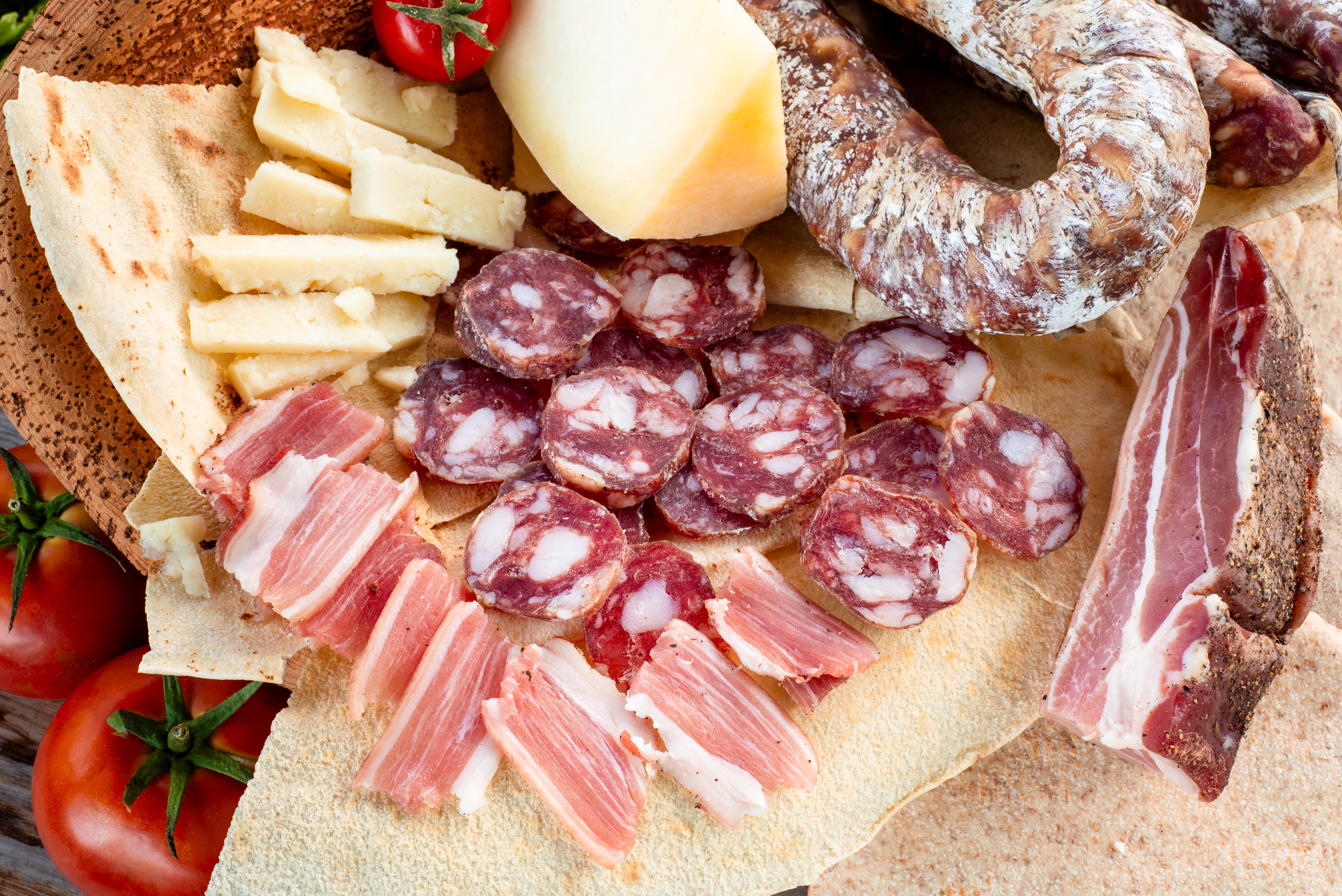 Rustikt sardinsk måltid med lokale delikatesser: krydrede pølser, lufttørret bacon, pecorino-ost og det tynde, sprøde carasau-brød - en smagfuld introduktion til Sardiniens køkken