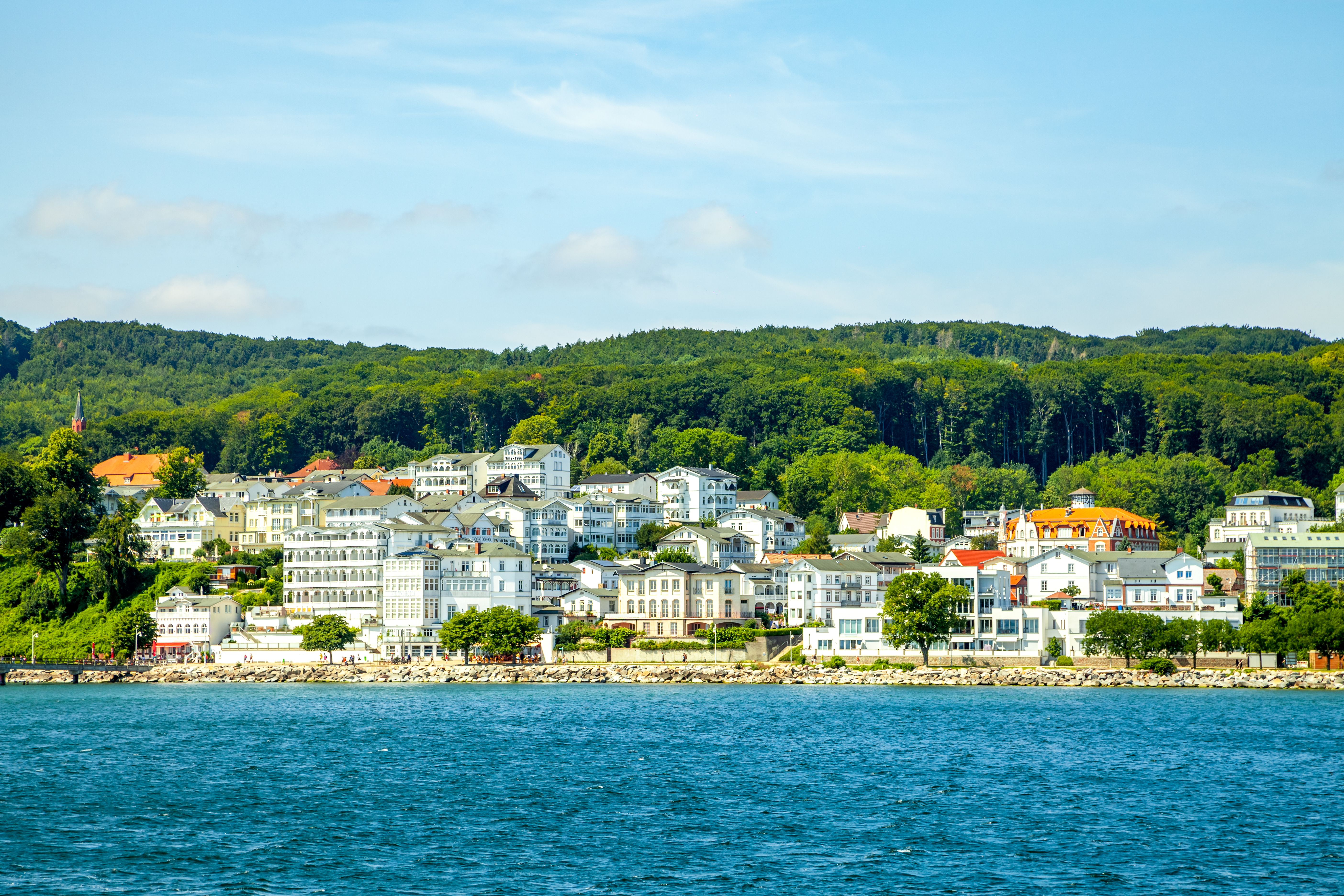 Idyllisk udsigt over Sassnitz på Rügen med smukke hvide feriebygninger ved Østersøkysten og grønne skove som naturlig baggrund