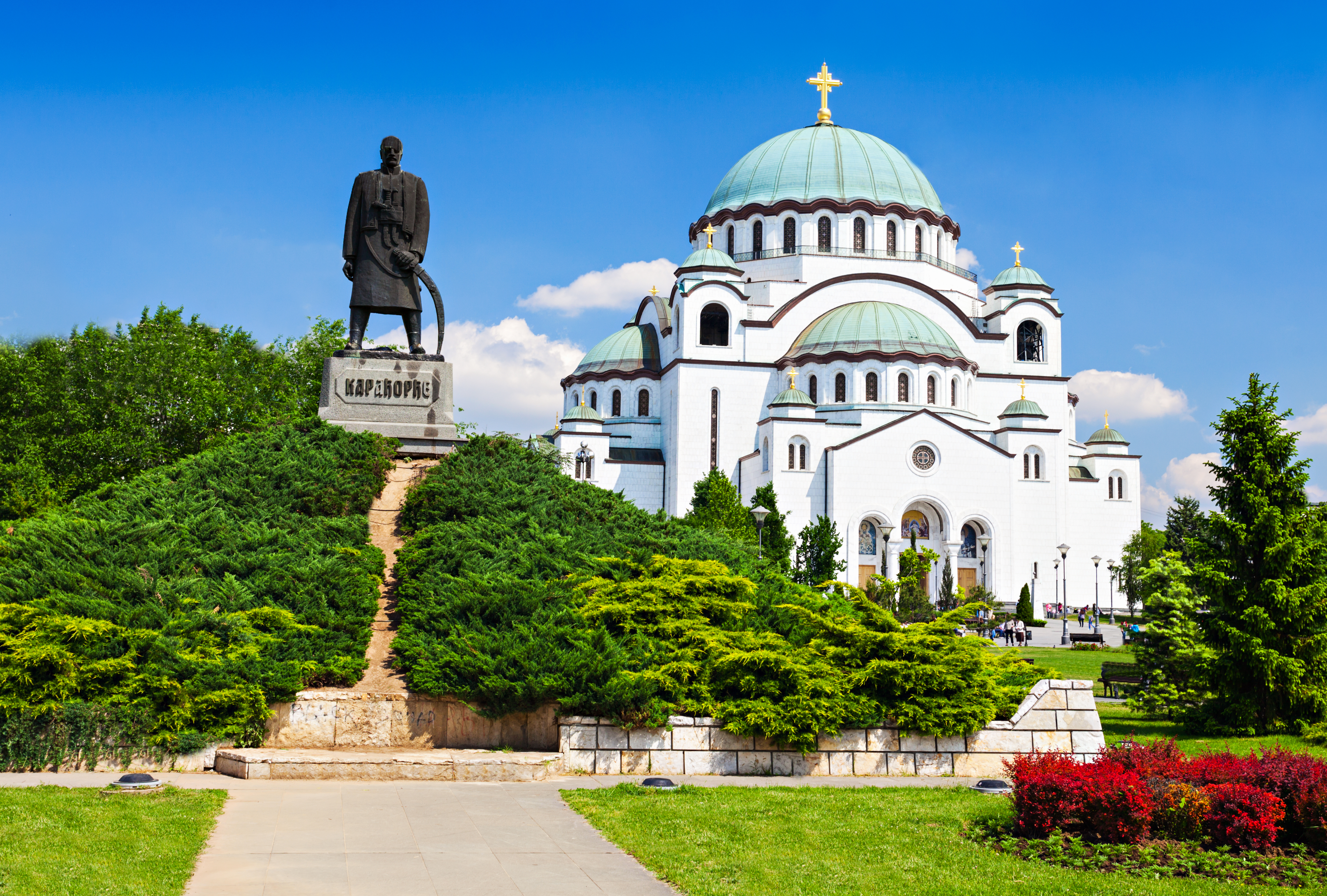 Den ortodokse Sava-katedral med turkisfarvede kupler og det historiske Karadjordje-monument i Beograd under klar blå himmel