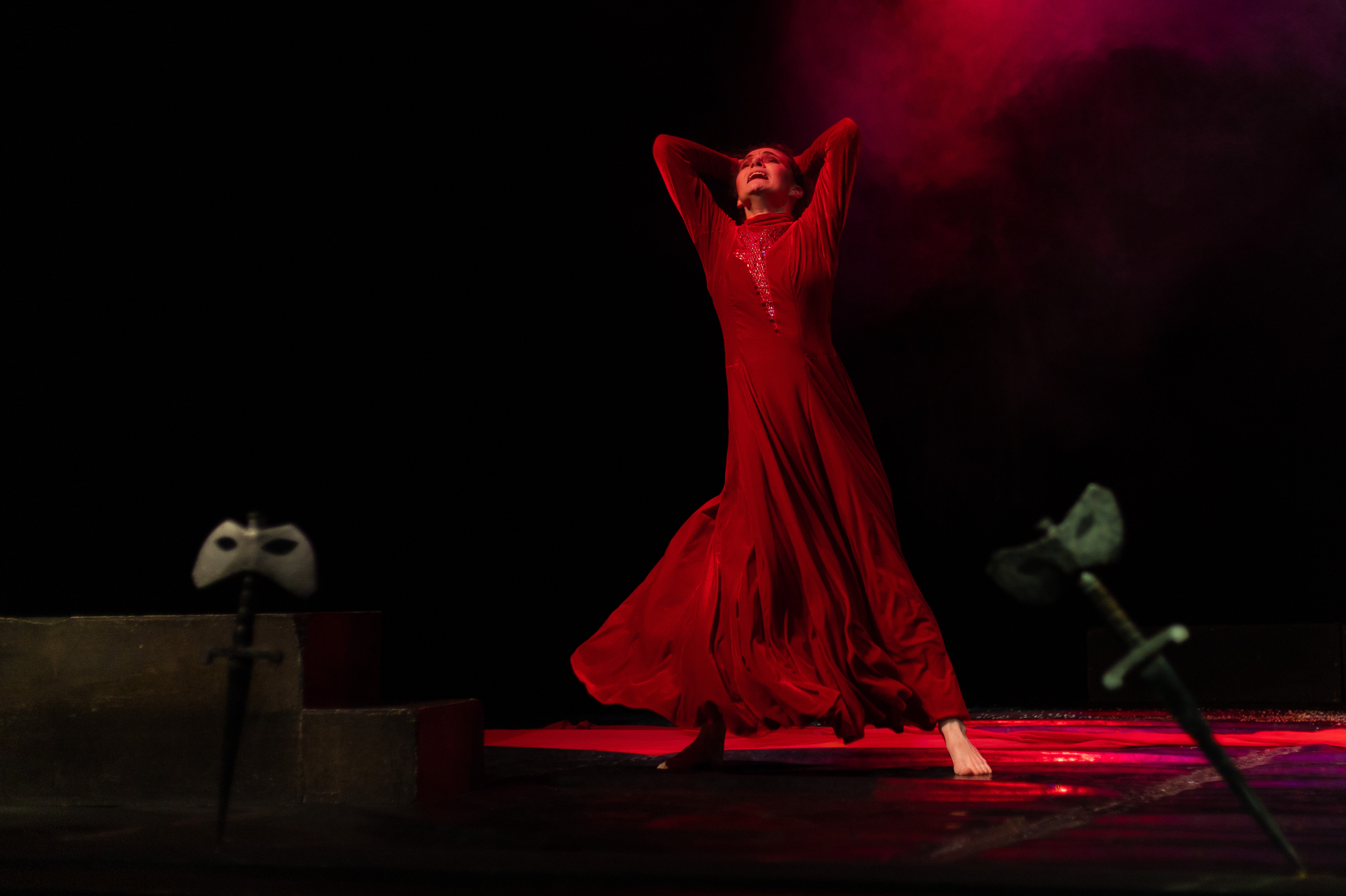 Sceneperformance med elegant danser i rød kjole og dramatisk lys