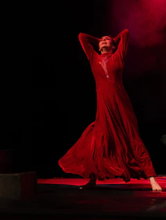 Sceneperformance med elegant danser i rød kjole og dramatisk lys