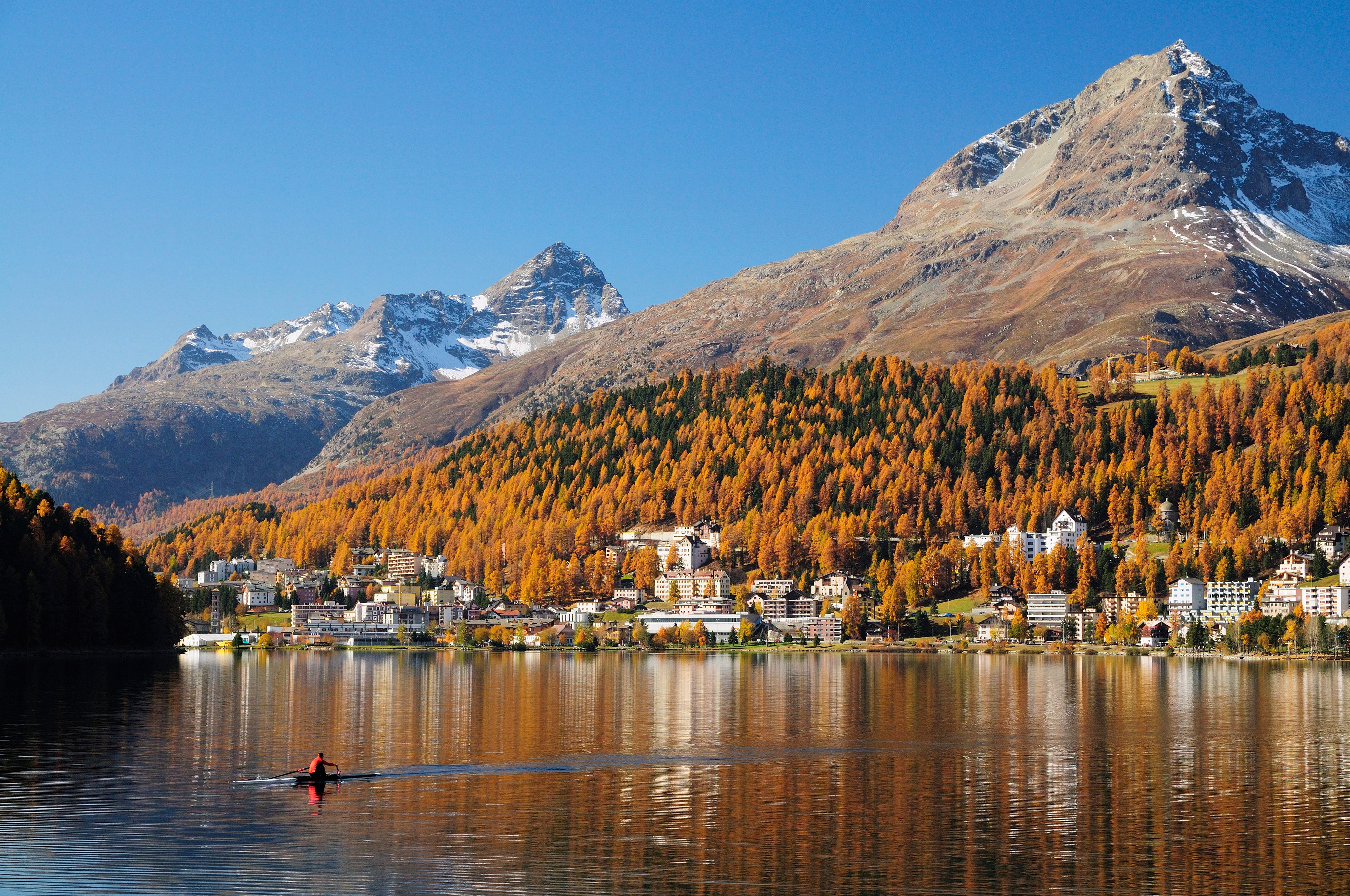 Magisk efterårsstemning ved St. Moritz-søen med orangegule skove og snedækkede bjergtinder i de schweiziske alper