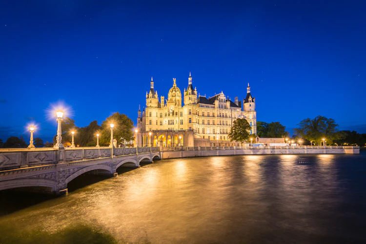 Schwerin Castle natbillede med oplyst facade og bro over soeen Tyskland
