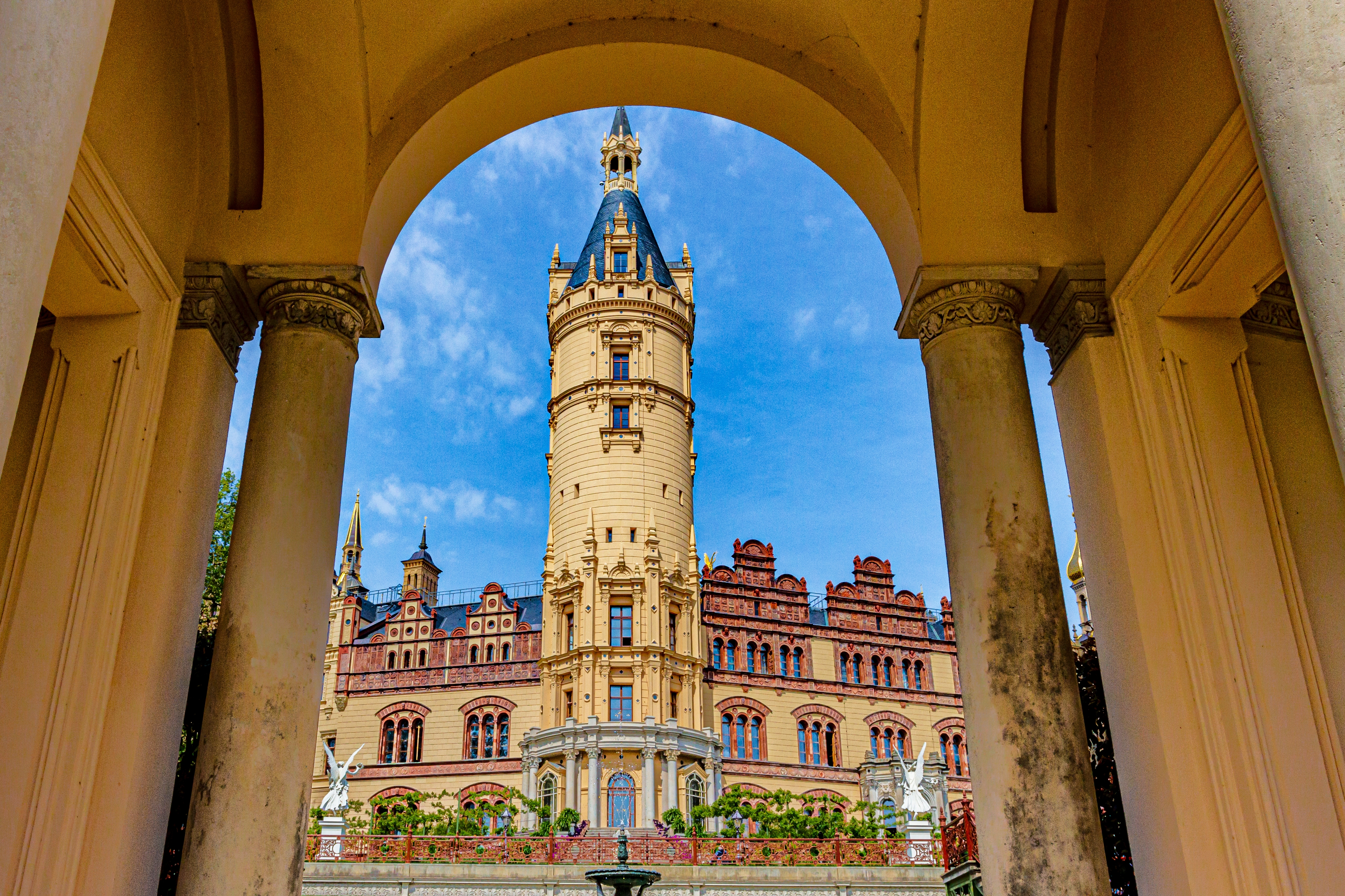 Schwerin Slot med det smukke tårn og rødbrune facade set gennem en historisk buegang i Nordtyskland