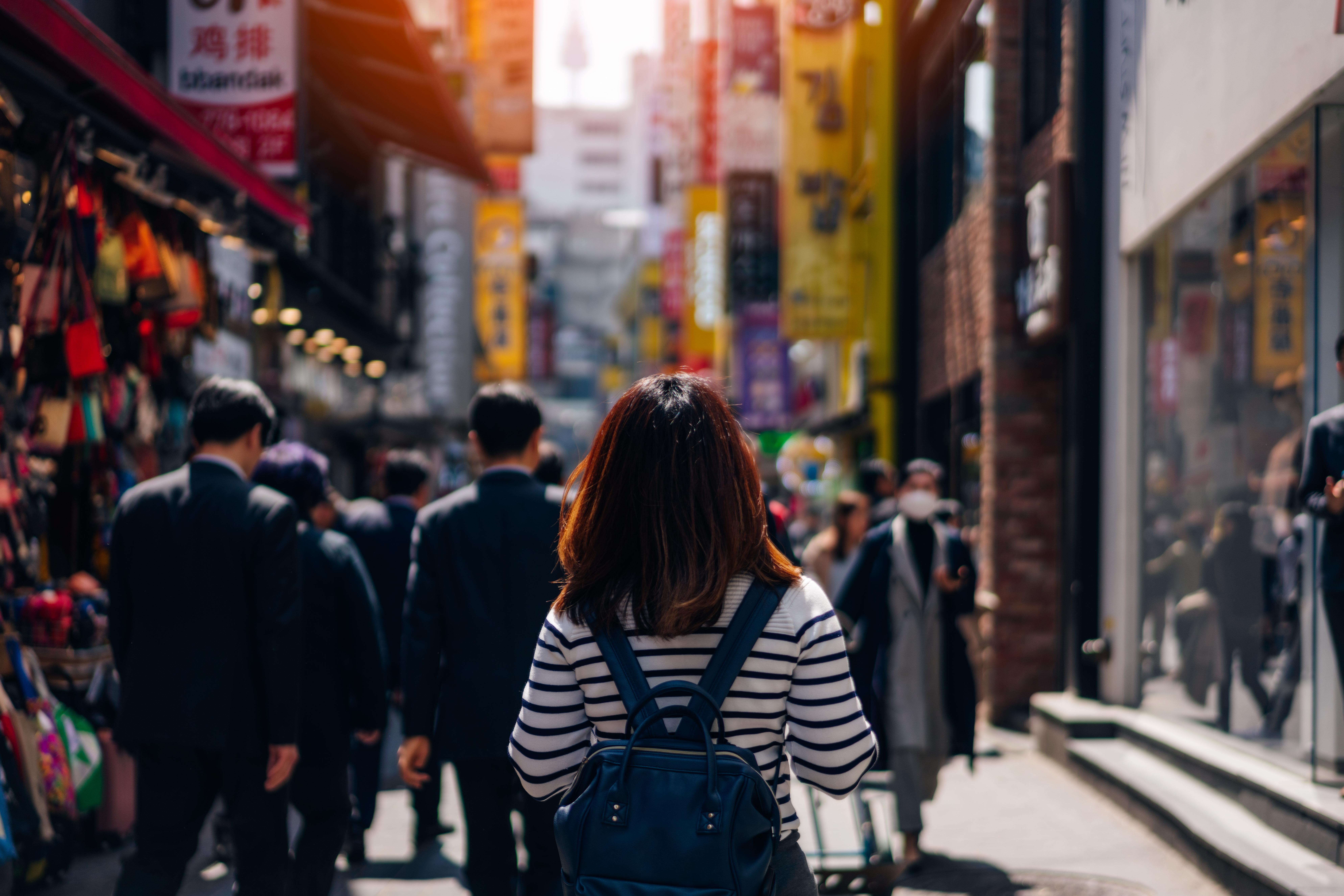 Ung kvinde vandrer gennem det populære shoppingområde Myeongdong i Seoul, omgivet af butikker og lokalt byliv