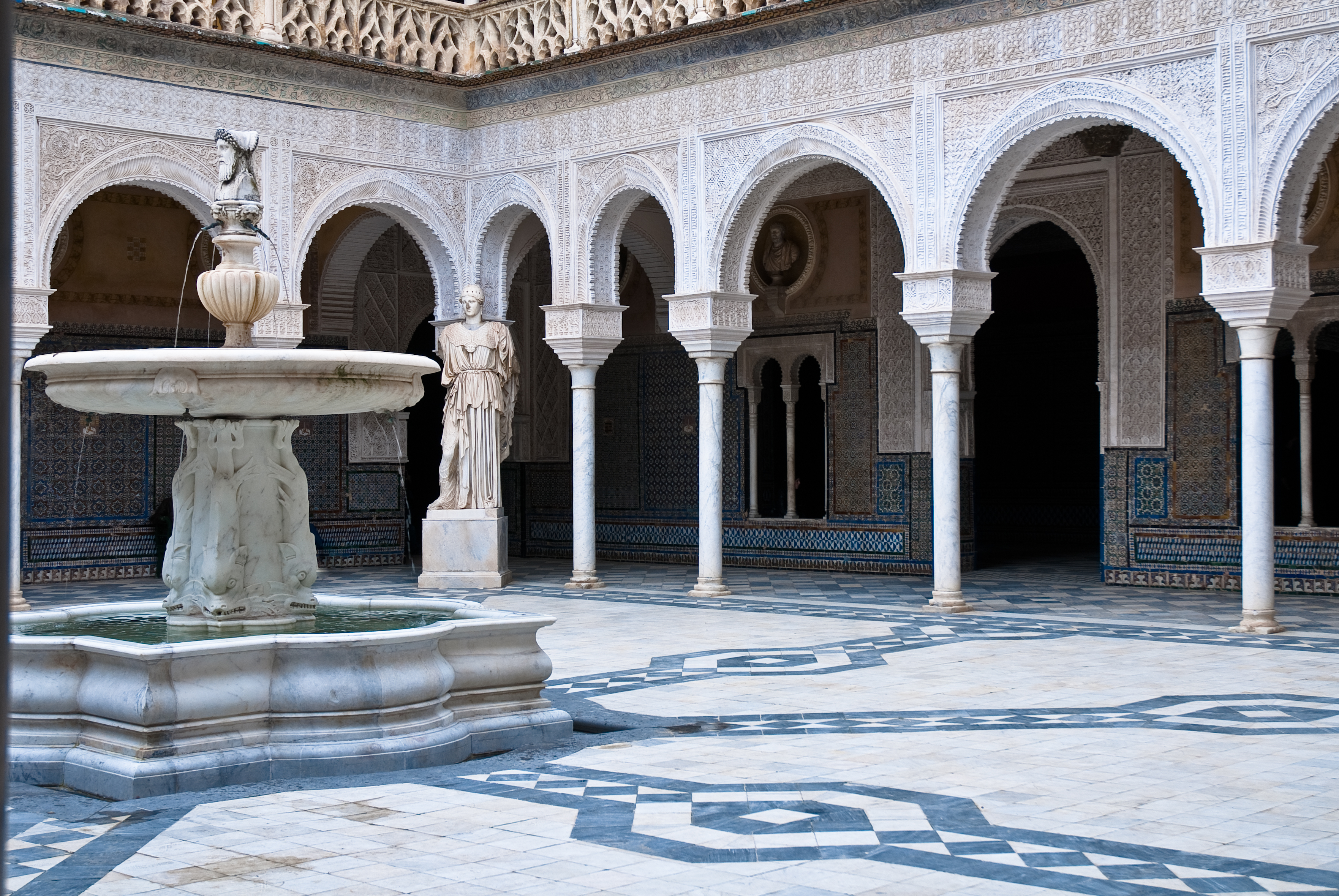 Andalusisk paladsarkitektur med flisearbejde og marmorfontæne i Sevilla, Spanien