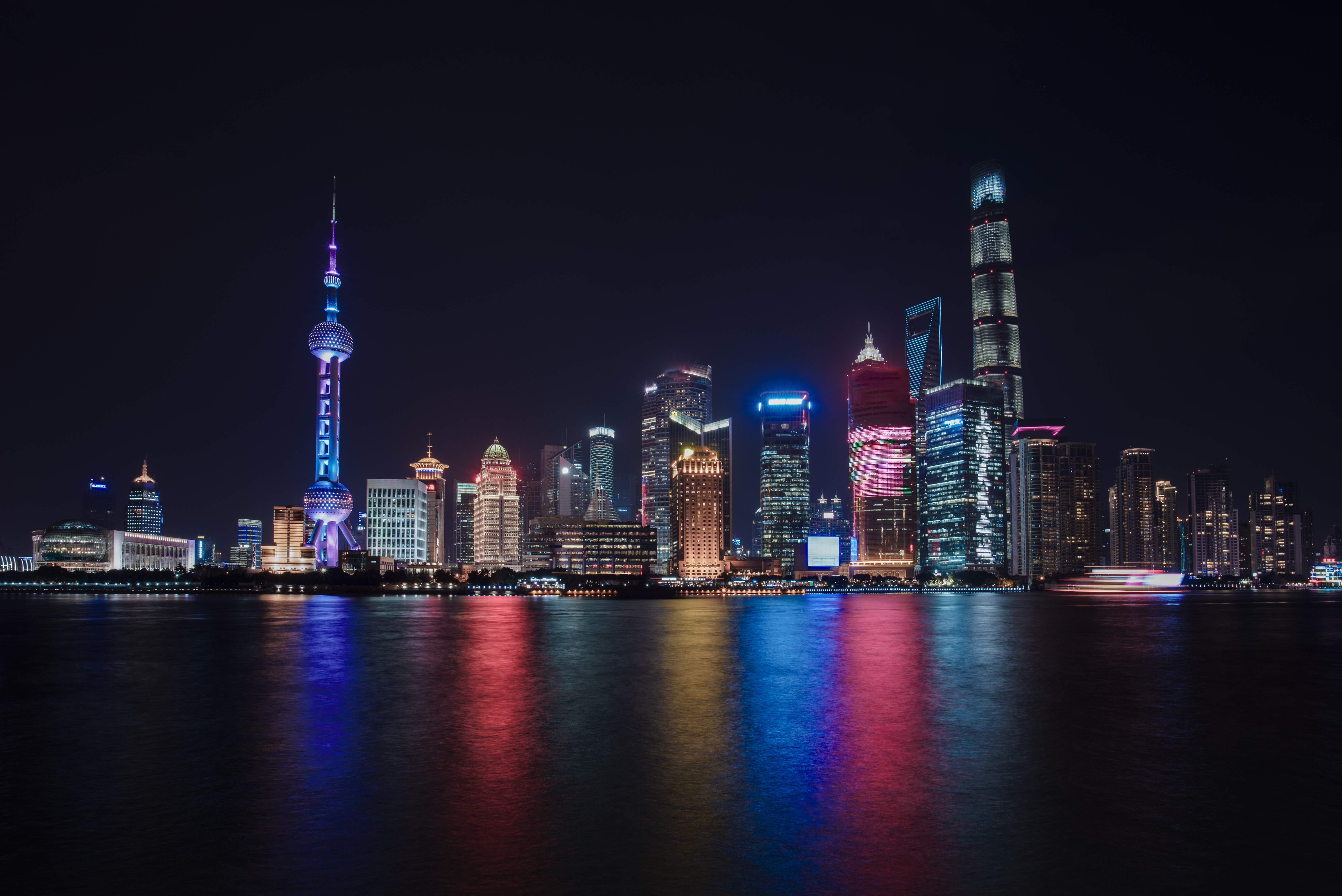 Spektakulær natlig udsigt over Shanghai i Kina med Oriental Pearl Tower og Pudongs skyskrabere reflekteret i floden