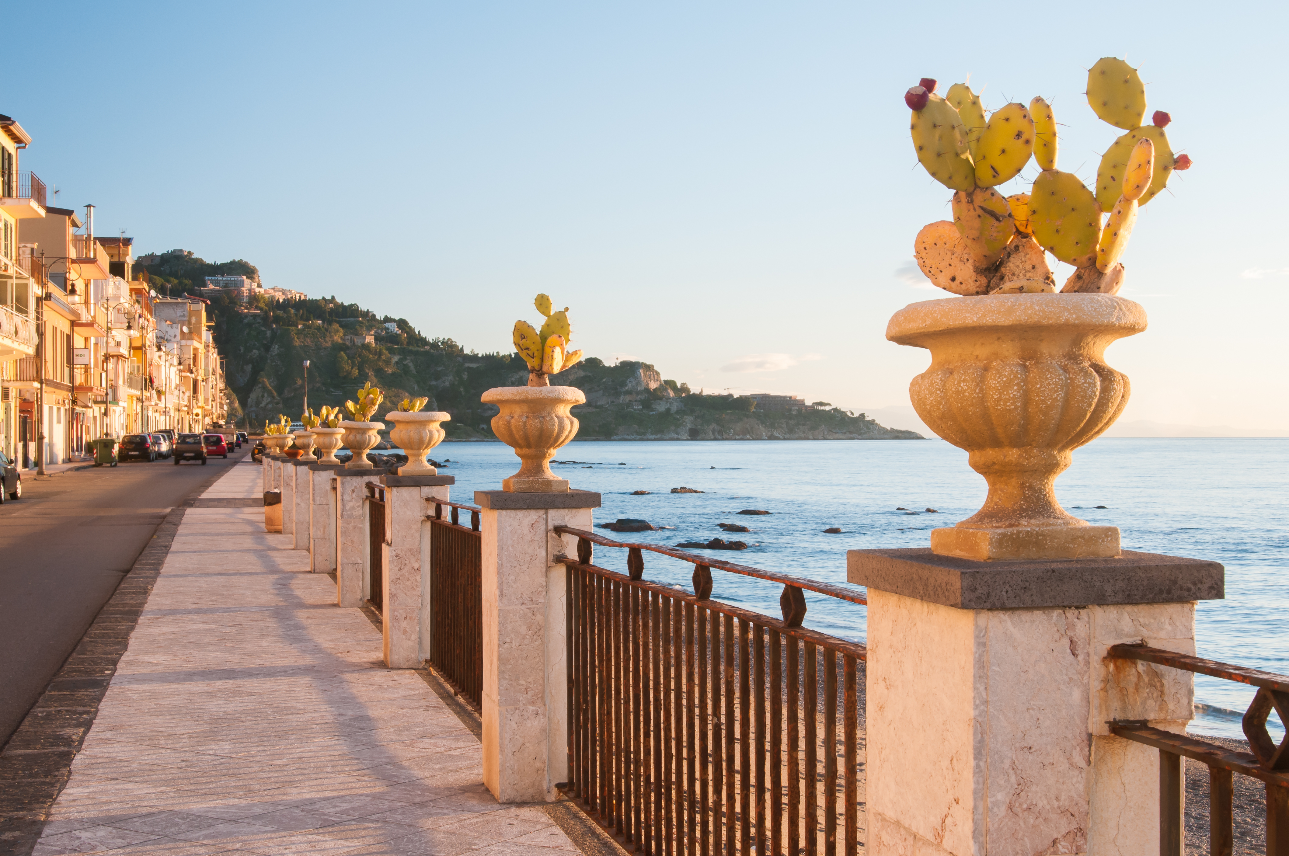 Charmerende havfront i turistbyen Giardini Naxos på Sicilien med karakteristiske kaktusplanter i dekorative stenvaser