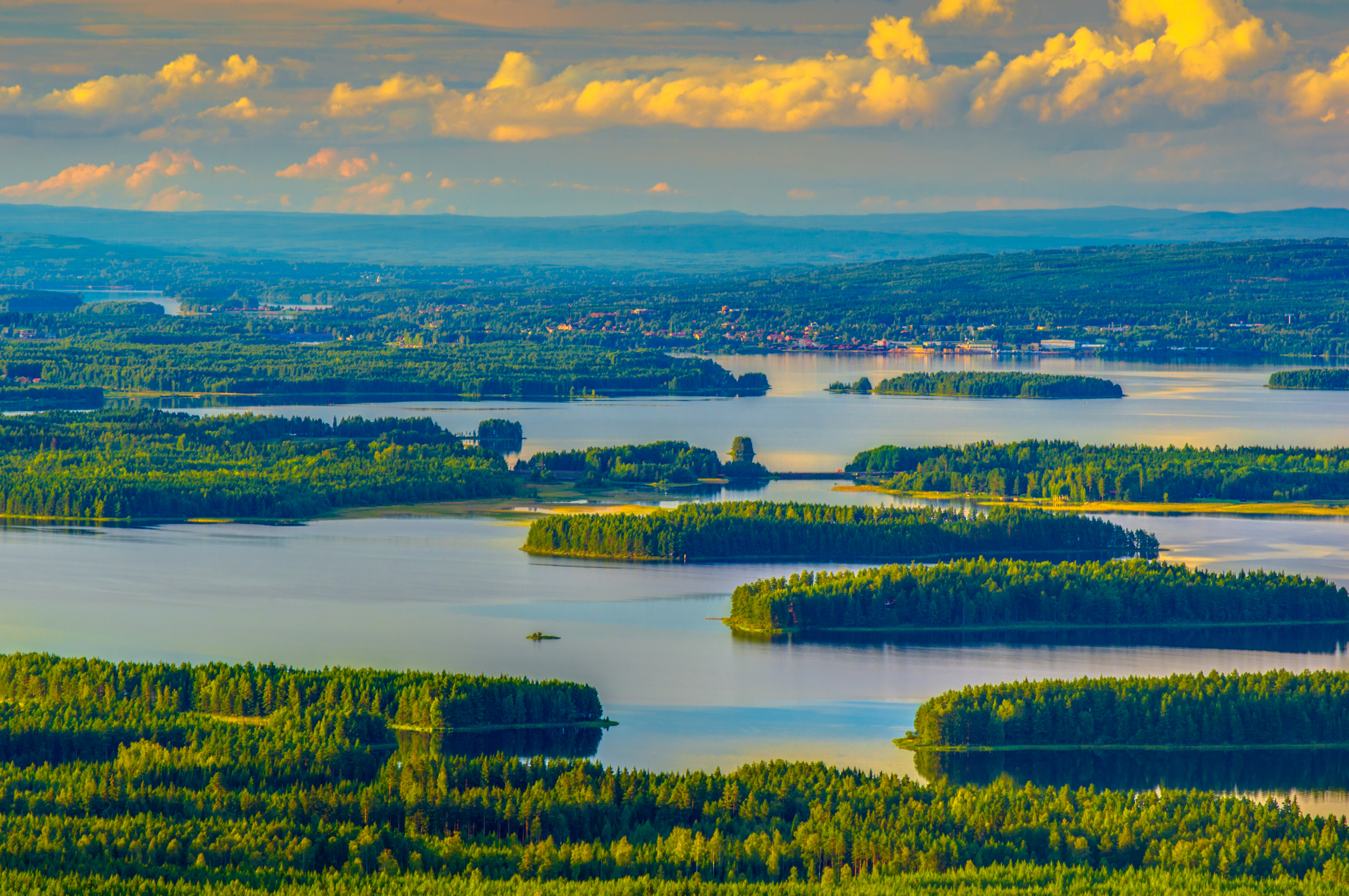 Naturskøn udsigt over Siljan-søen i Dalarna, Sverige, med frodige skovklædte øer og blå sommerhimmel