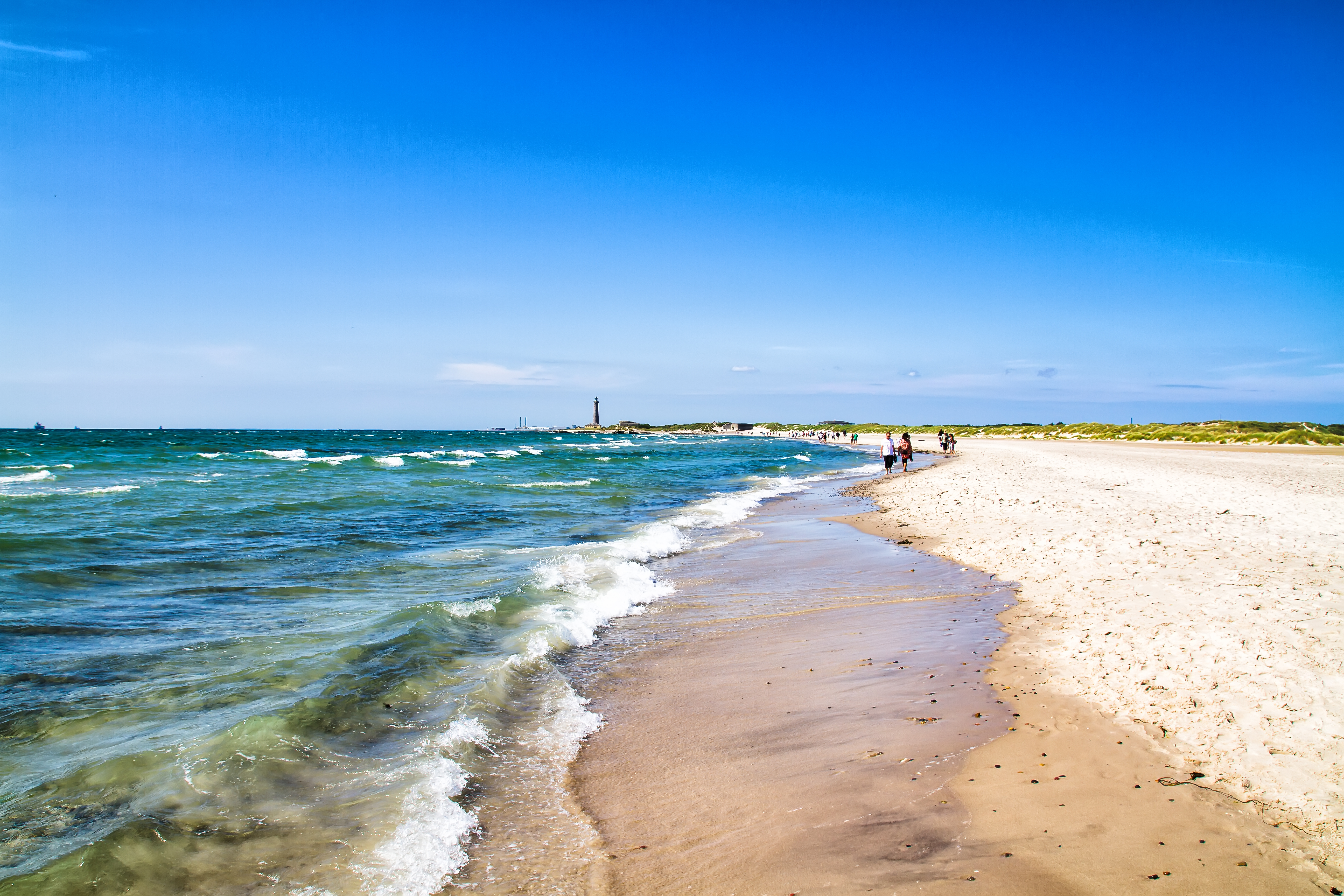 Grenen ved Skagen i Nordjylland – Danmarks nordligste punkt med bred sandstrand, turkist hav og turister på sommerferie langs kysten