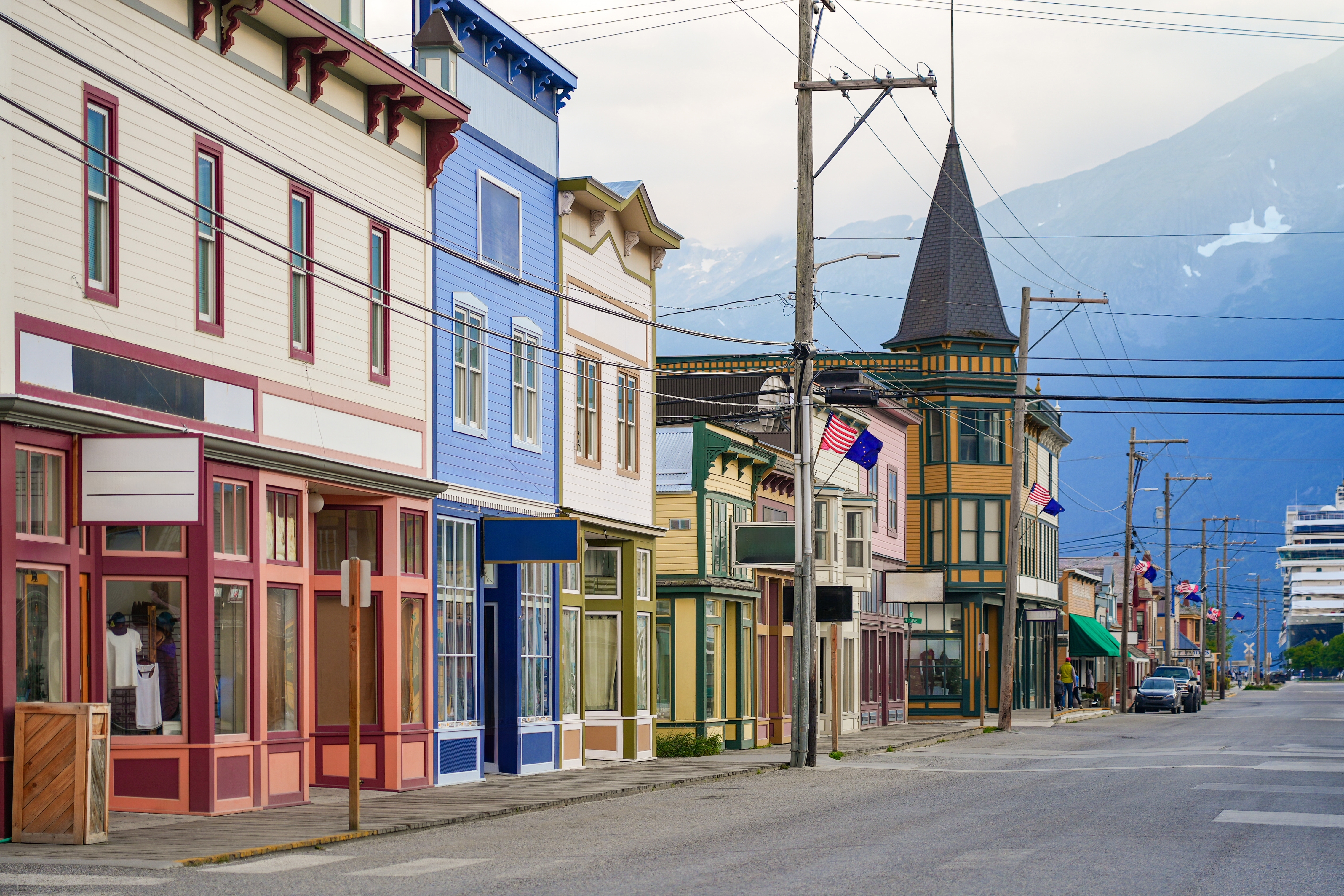 Malerisk gadescene i det historiske Skagway, Alaska, med velbevarede farverige bygninger fra guldrush-perioden og smukke bjergtoppe i det fjerne