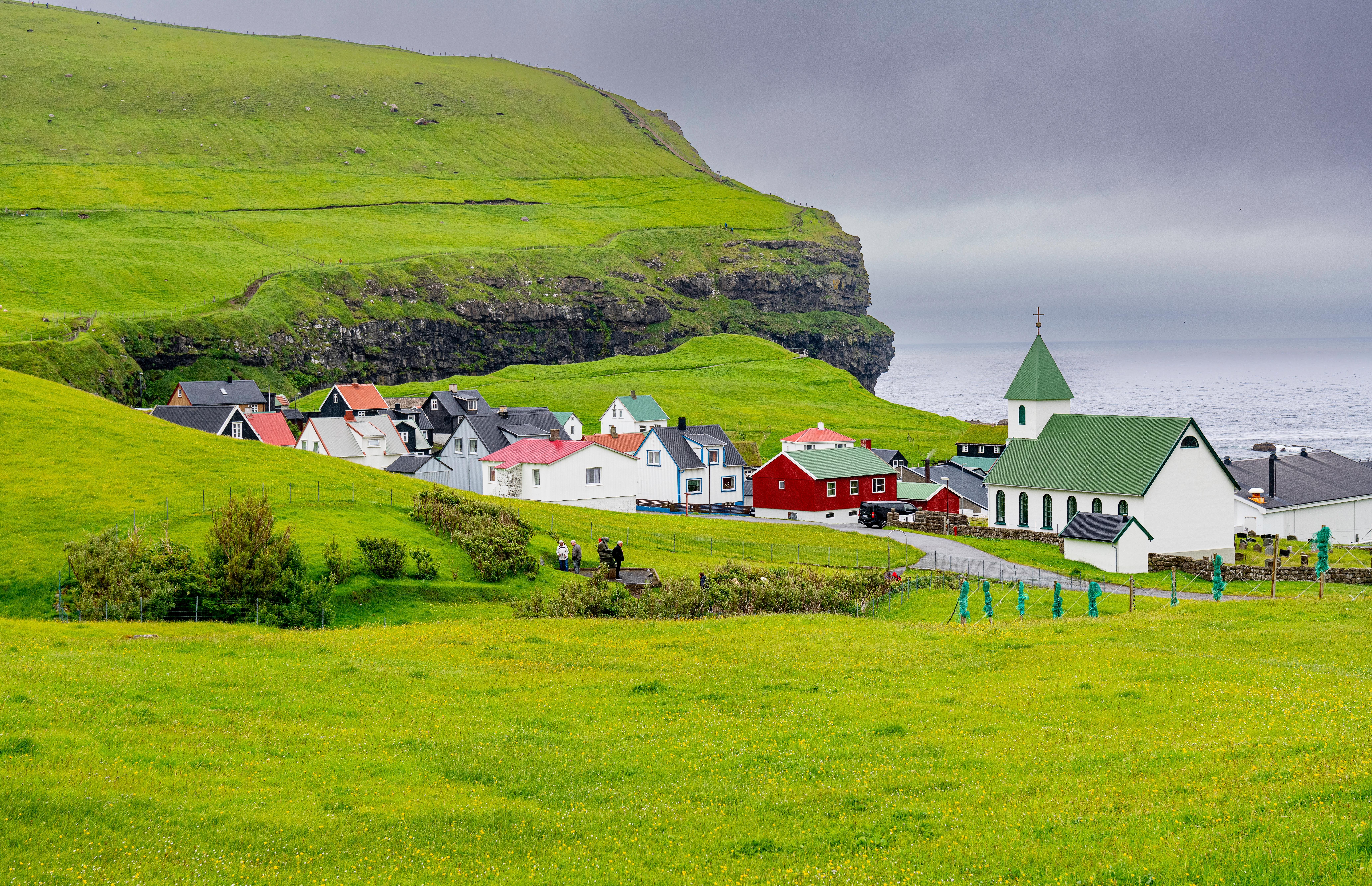 Traditionel skandinavisk landsby på Færøerne med røde og hvide huse i dramatisk natur