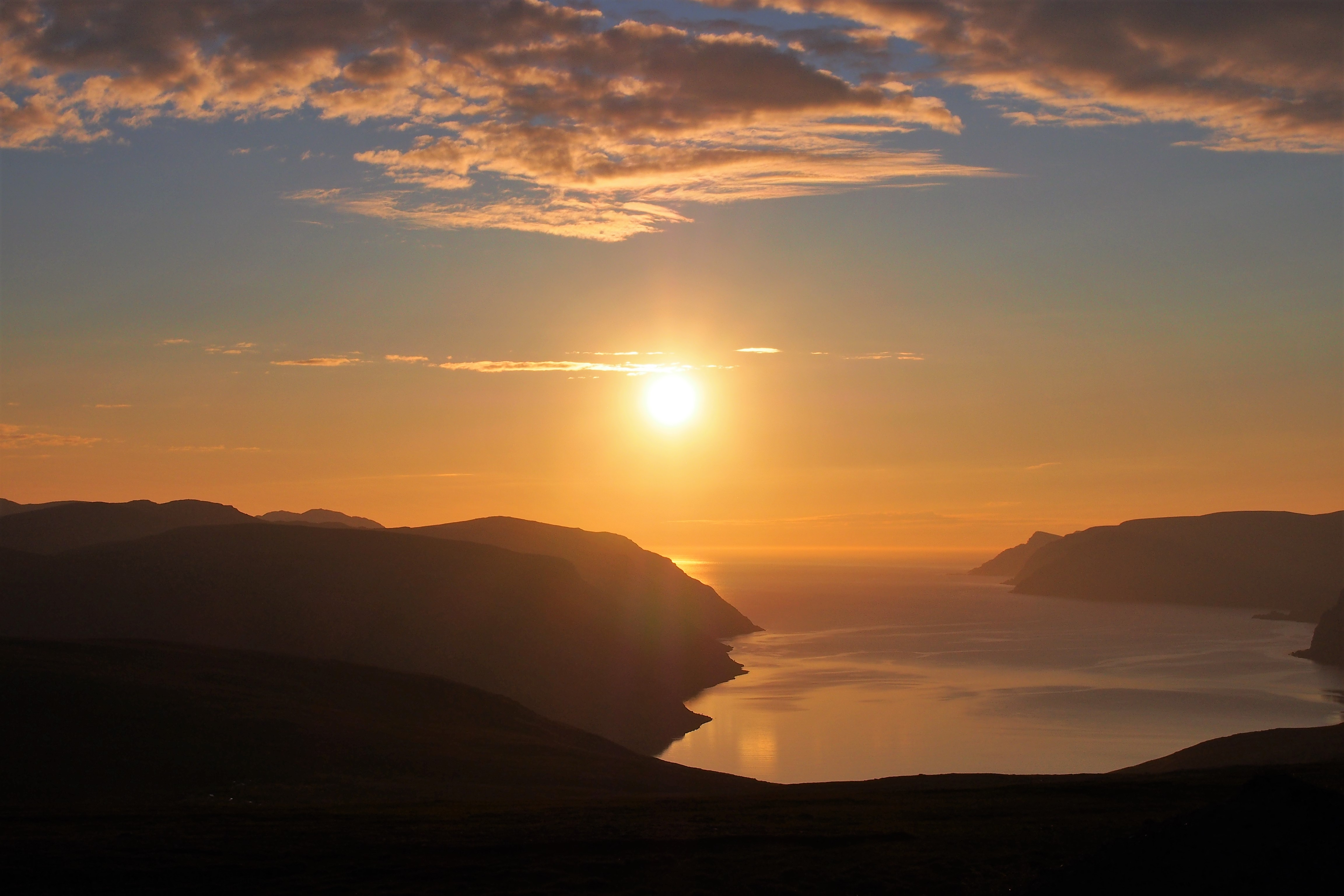 Storslået skandinavisk fjordlandskab i gylden solnedgangslys