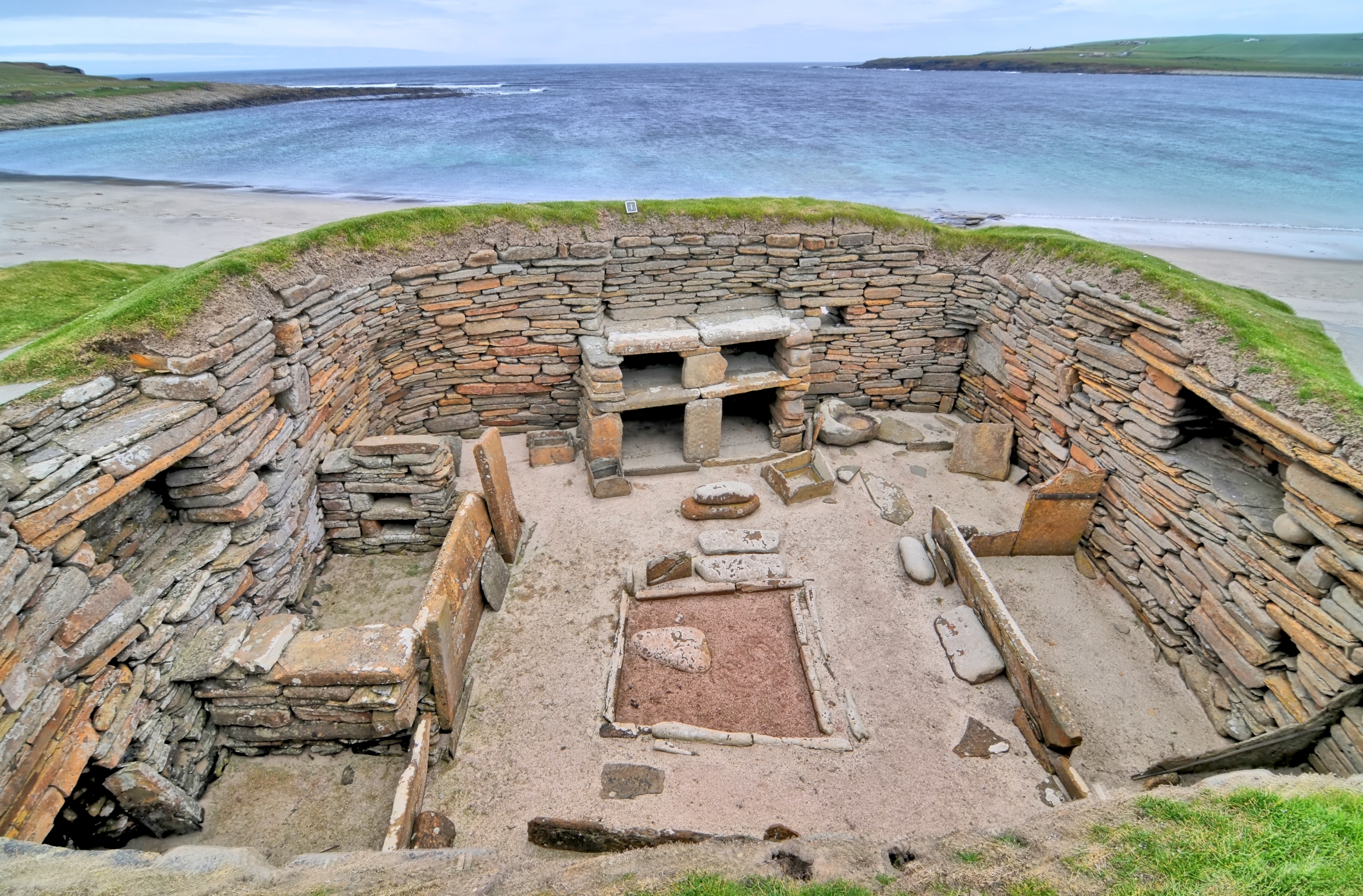 Udsigt over den UNESCO-listede forhistoriske udgravning Skara Brae på Orkneyøerne, Skotland, med imponerende stenbyggede huse og bevaret stenmobiliar ved Atlanterhavskysten