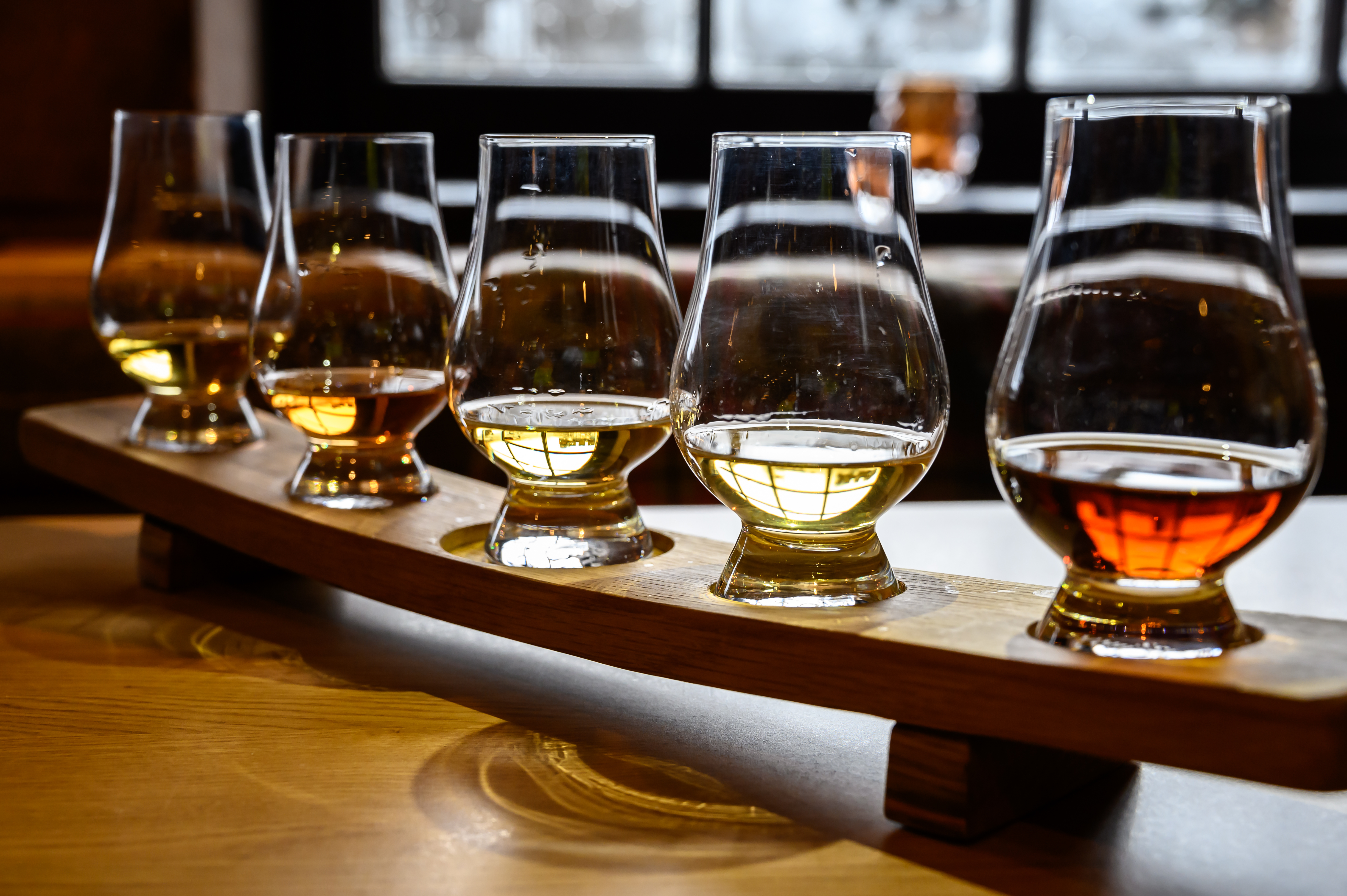 Whisky flight med seks glas forskellige skotske single malts og blended whiskies serveret på en træplade under destilleribesøg i Skotland