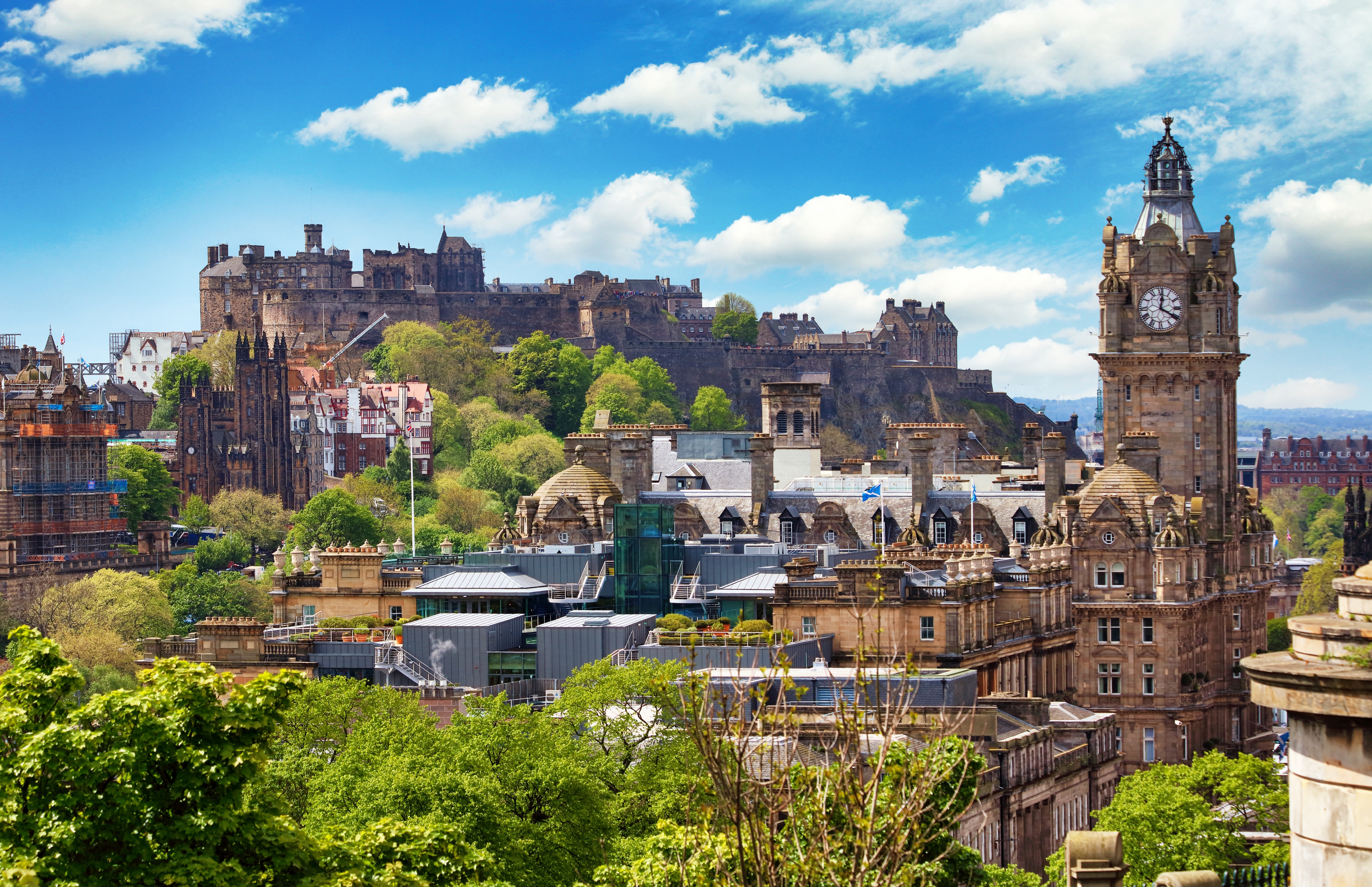 Panoramaudsigt over Edinburgh med det majestætiske Edinburgh Castle på klippetoppen og Balmoral Hotels klokketårn omgivet af historiske bygninger i Skotland