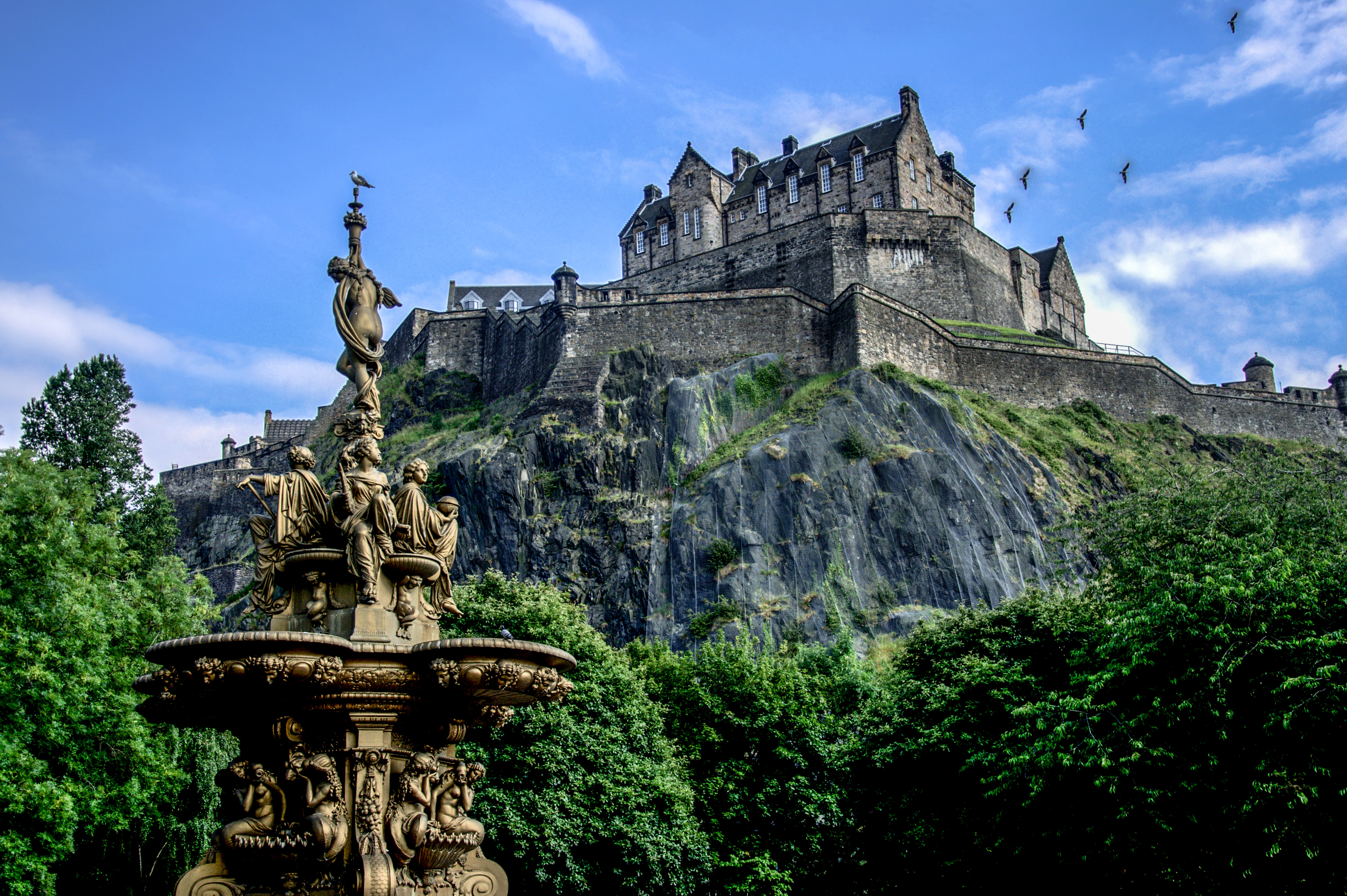 Edinburgh Castle tronende på klippe med ornamental fontæne i Princes Street Gardens