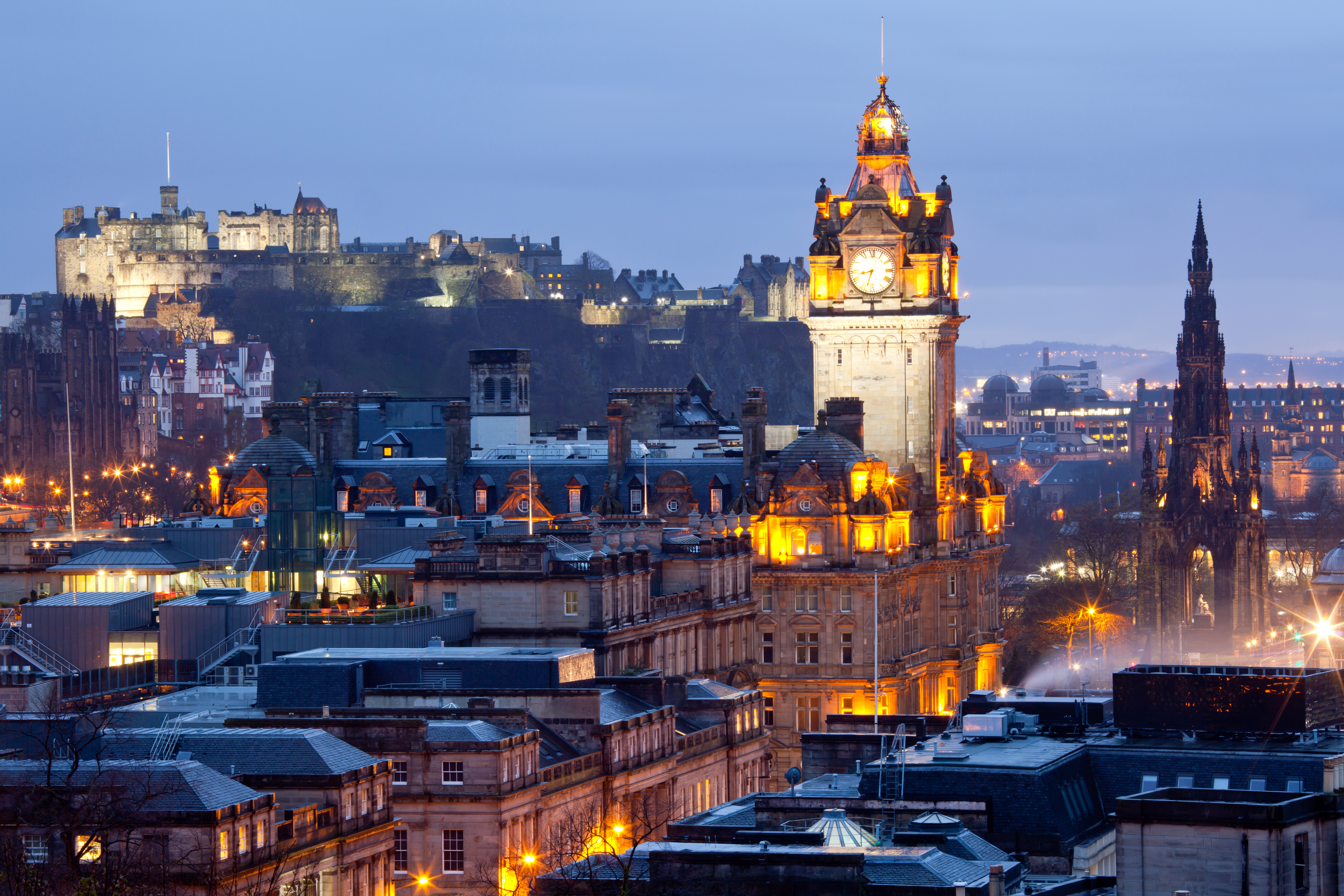 Panoramaview over Edinburgh om aftenen med slot og kirkespir, Skotland
