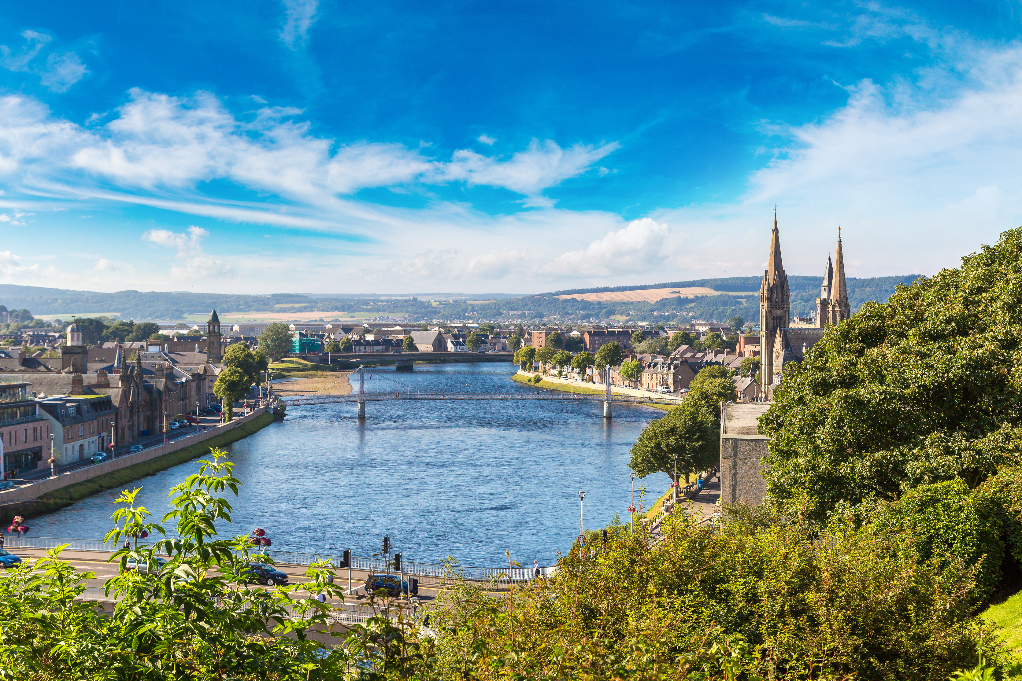 Charmerende bybillede af Inverness i Skotland med floden Ness, broer og historiske bygninger under en klar sommerhimmel