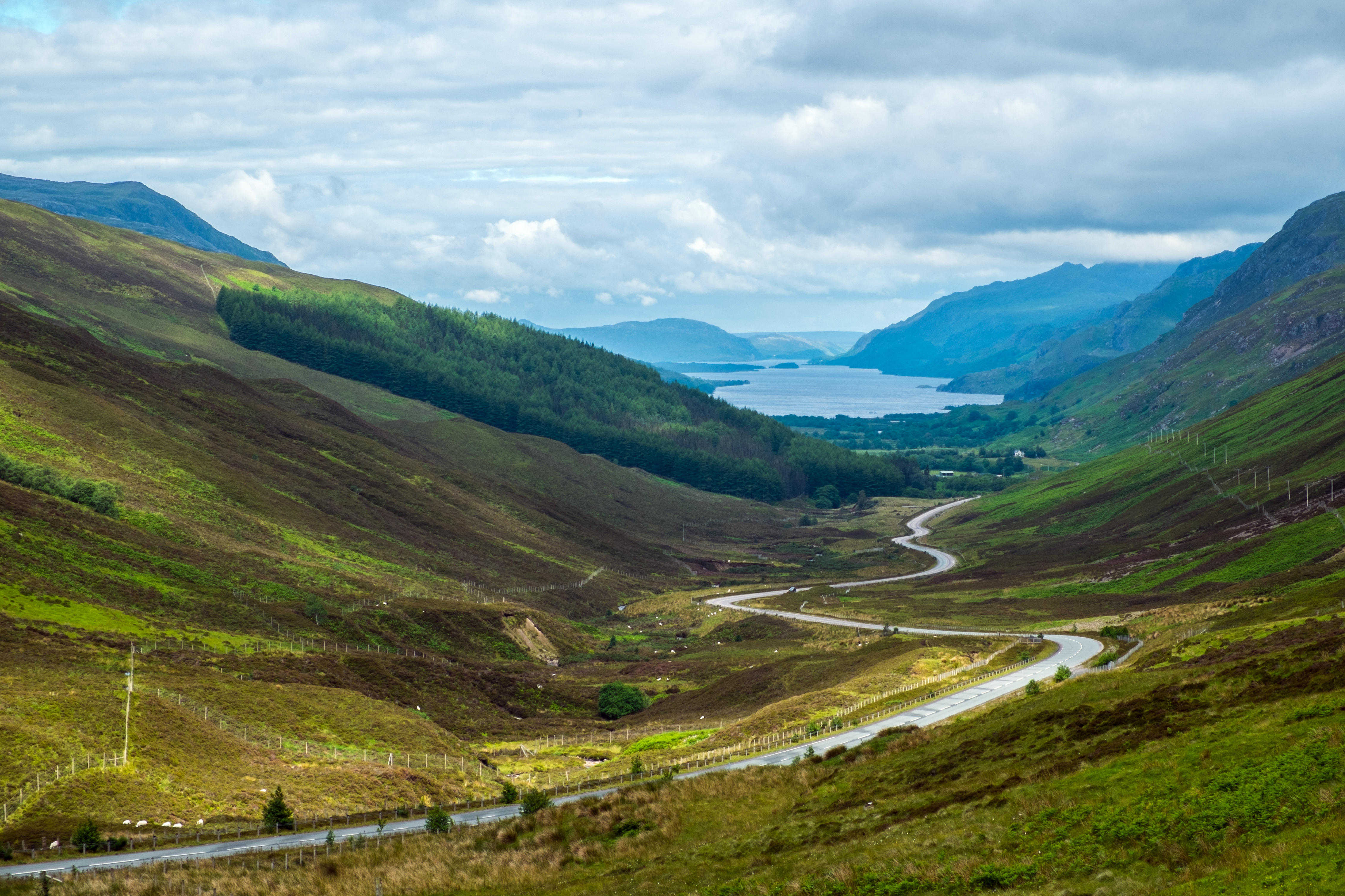 Imponerende udsigt over Loch Maree fra Glen Docherty på den populære North Coast 500 køretur i Skotlands højlande, omgivet af grønne bjerge og dramatisk skyet himmel