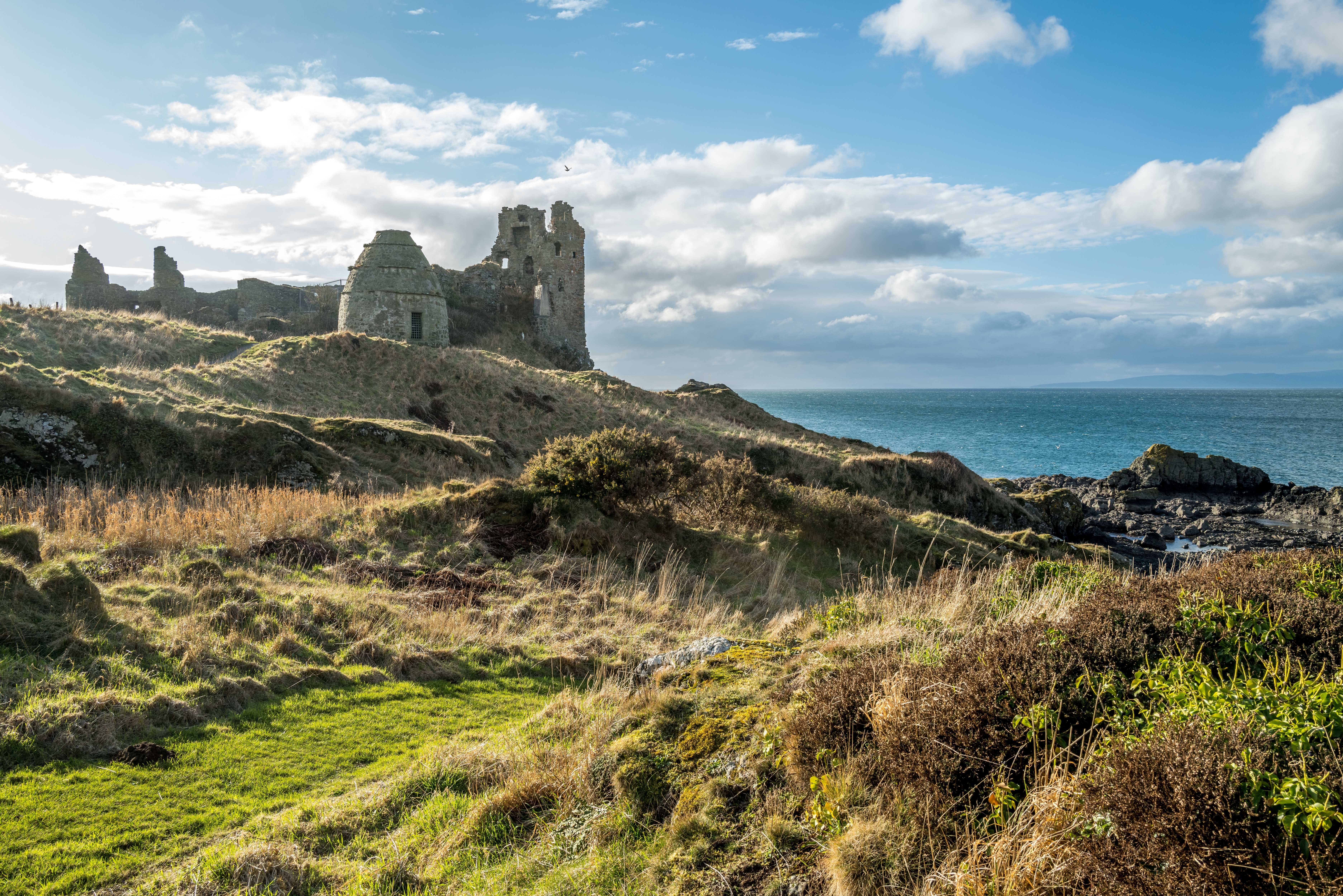 Imponerende ruiner af Dunure Castle i Burns Country, South Ayrshire, Skotland, med havet gnistrende i baggrunden