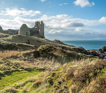 Imponerende ruiner af Dunure Castle i Burns Country, South Ayrshire, Skotland, med havet gnistrende i baggrunden