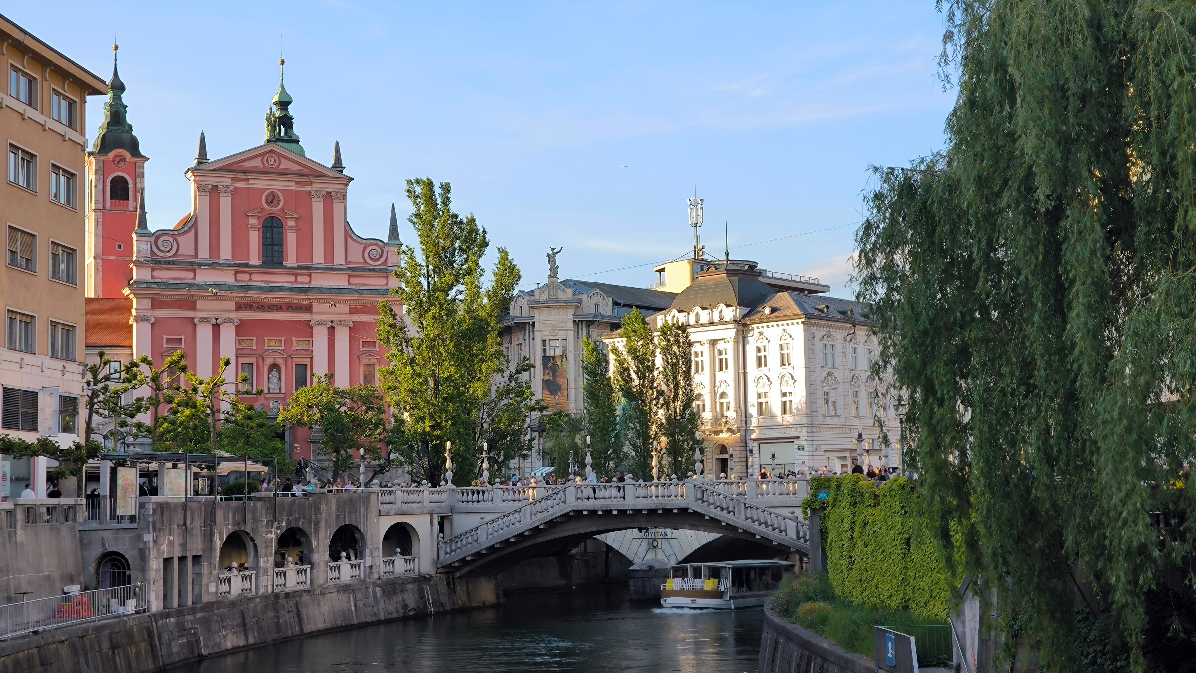 Charmerende flodbred i Ljubljana med den berømte Tromostovje bro og farverige barokbygninger