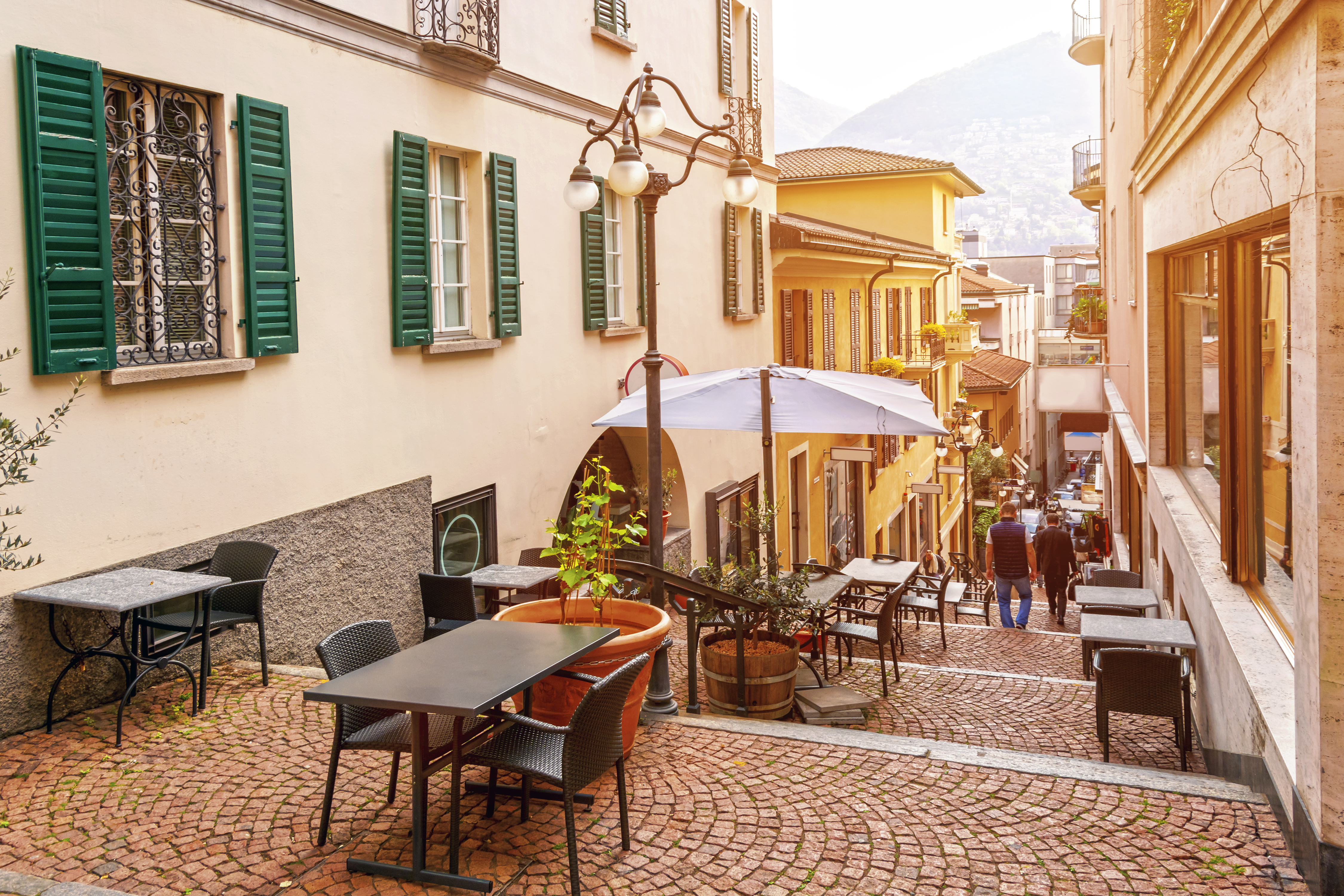 Smal gade med hyggelige caféer og restauranter i den gamle bydel af Lugano ved foden af Alperne, Ticino-kantonen, Schweiz