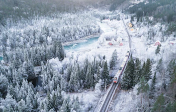 Jernbanetransport gennem frostvinter landskab i Norge med tæt sneskov