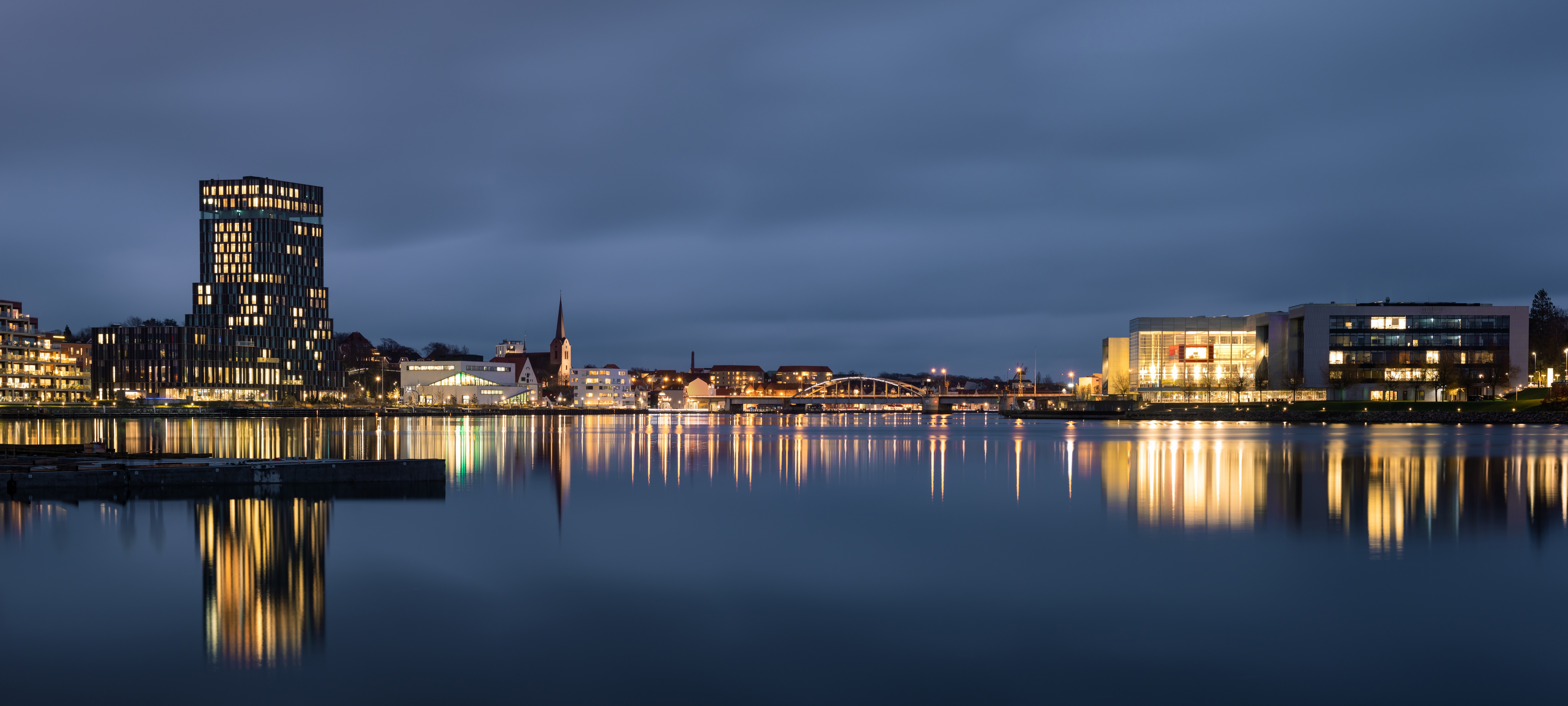 Sønderborg havn med aftenlys og moderne arkitektur reflekteret i det stille vand