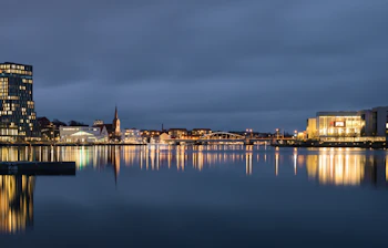 Sønderborg havn med aftenlys og moderne arkitektur reflekteret i det stille vand