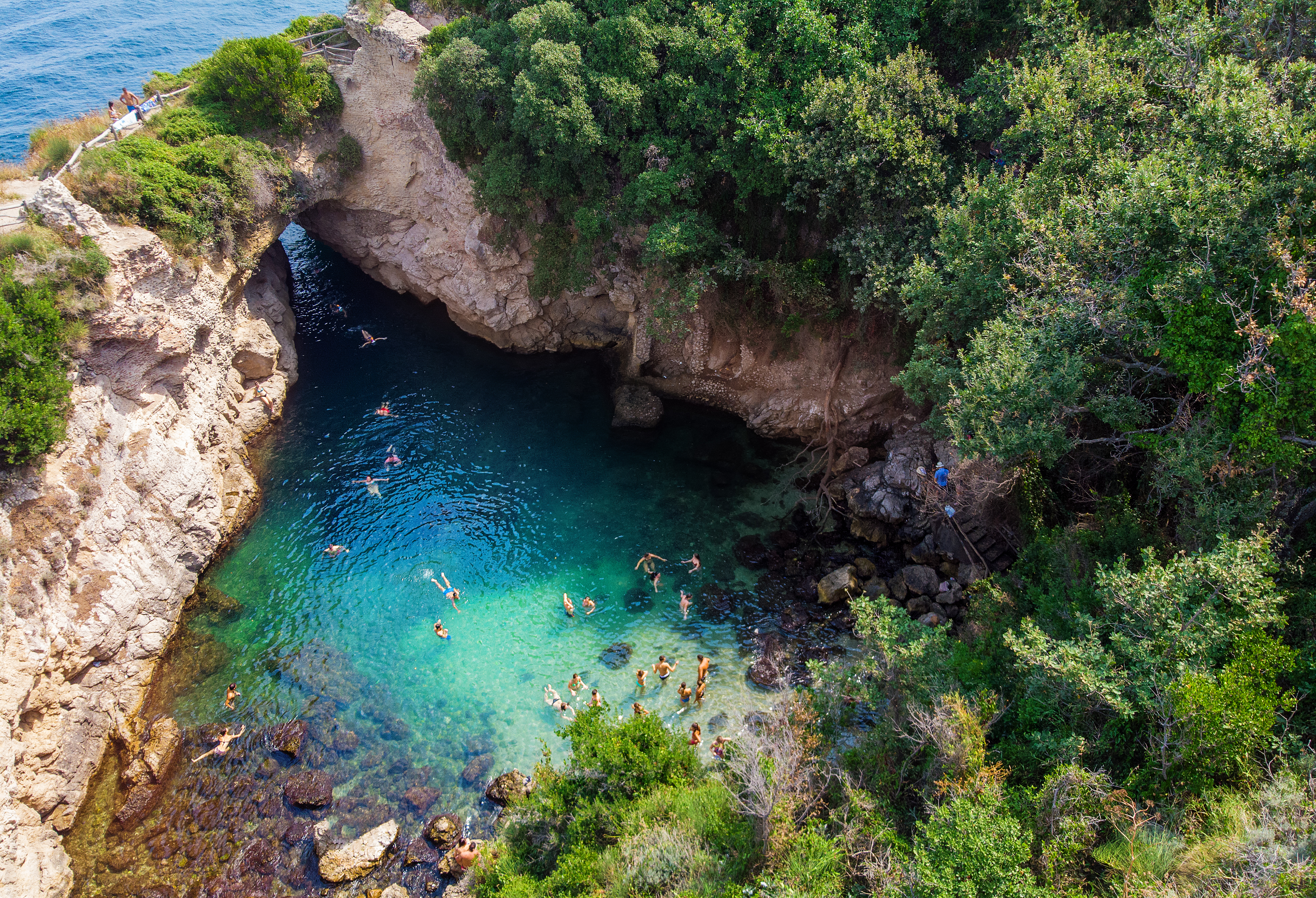 Idyllisk bugt ved Regina Giovannas bad i Sorrento med turkisblåt vand og frodige klipper hvor turister nyder en svømmetur