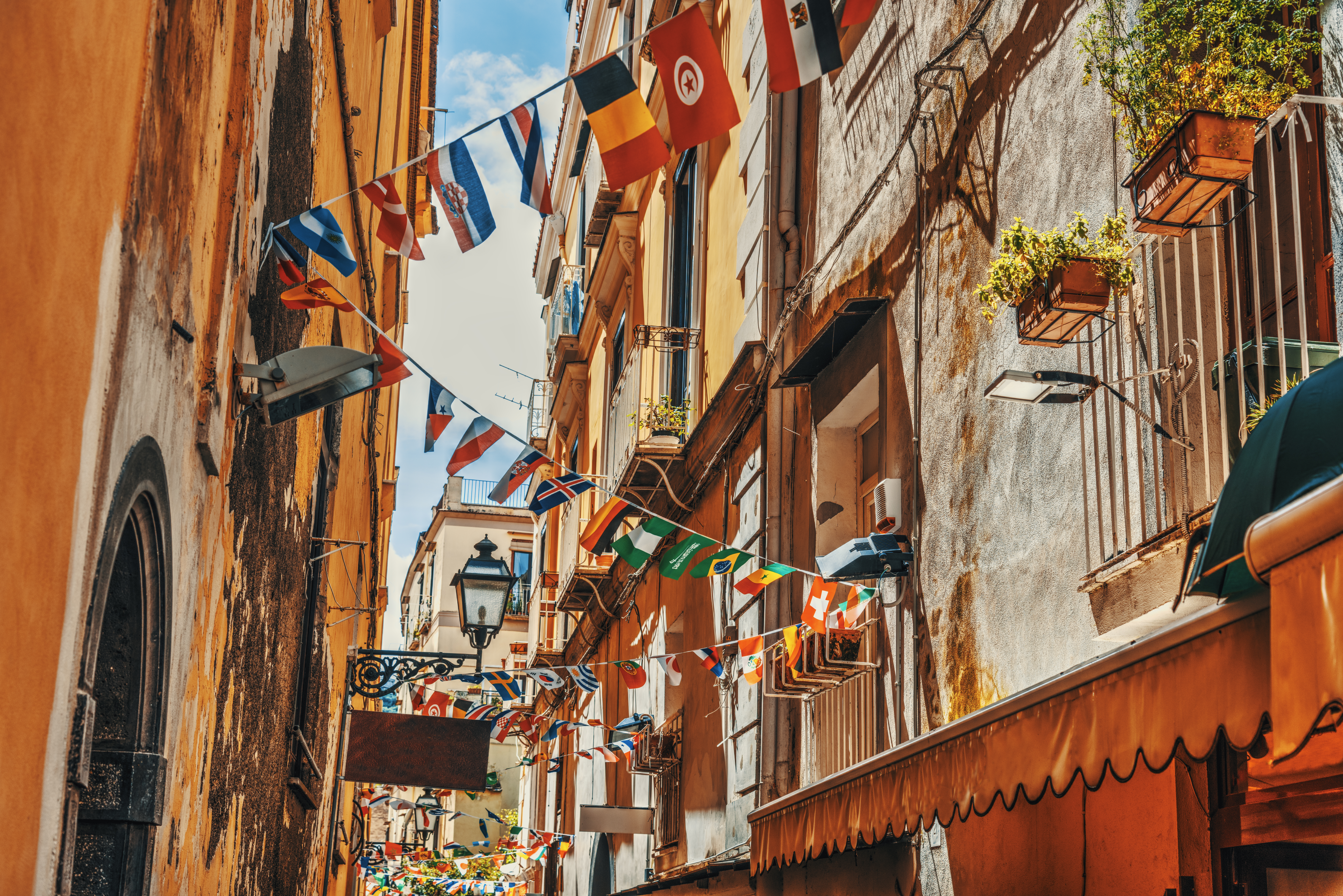 Malerisk smal gade med farverige flag og varme bygningsfacader i den gamle bydel af Sorrento, et perfekt eksempel på italiensk kystcharme