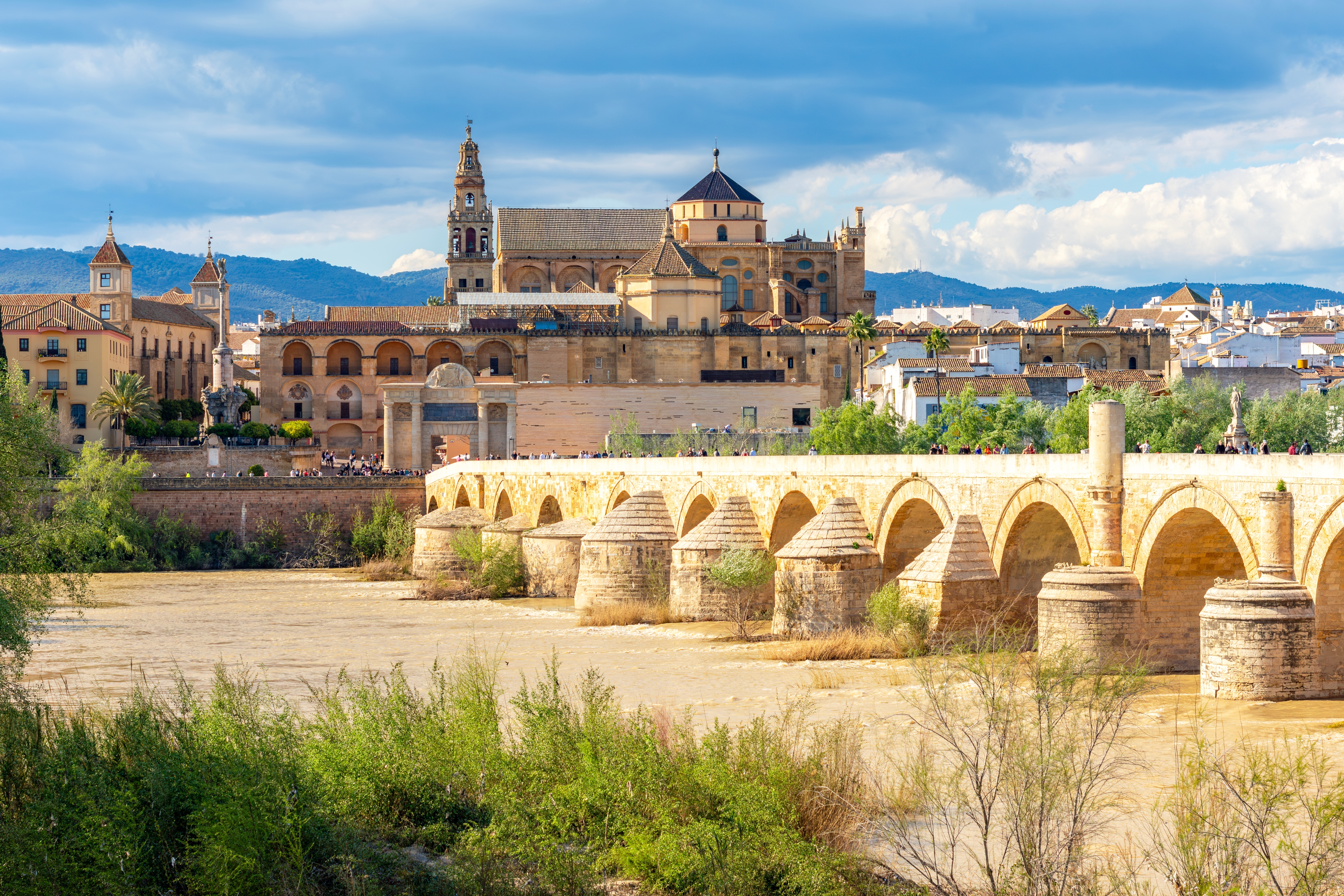 Praegtig romersk bro med stenbuer og Mezquita-komplekset i den historiske by Cordoba i Andalusien