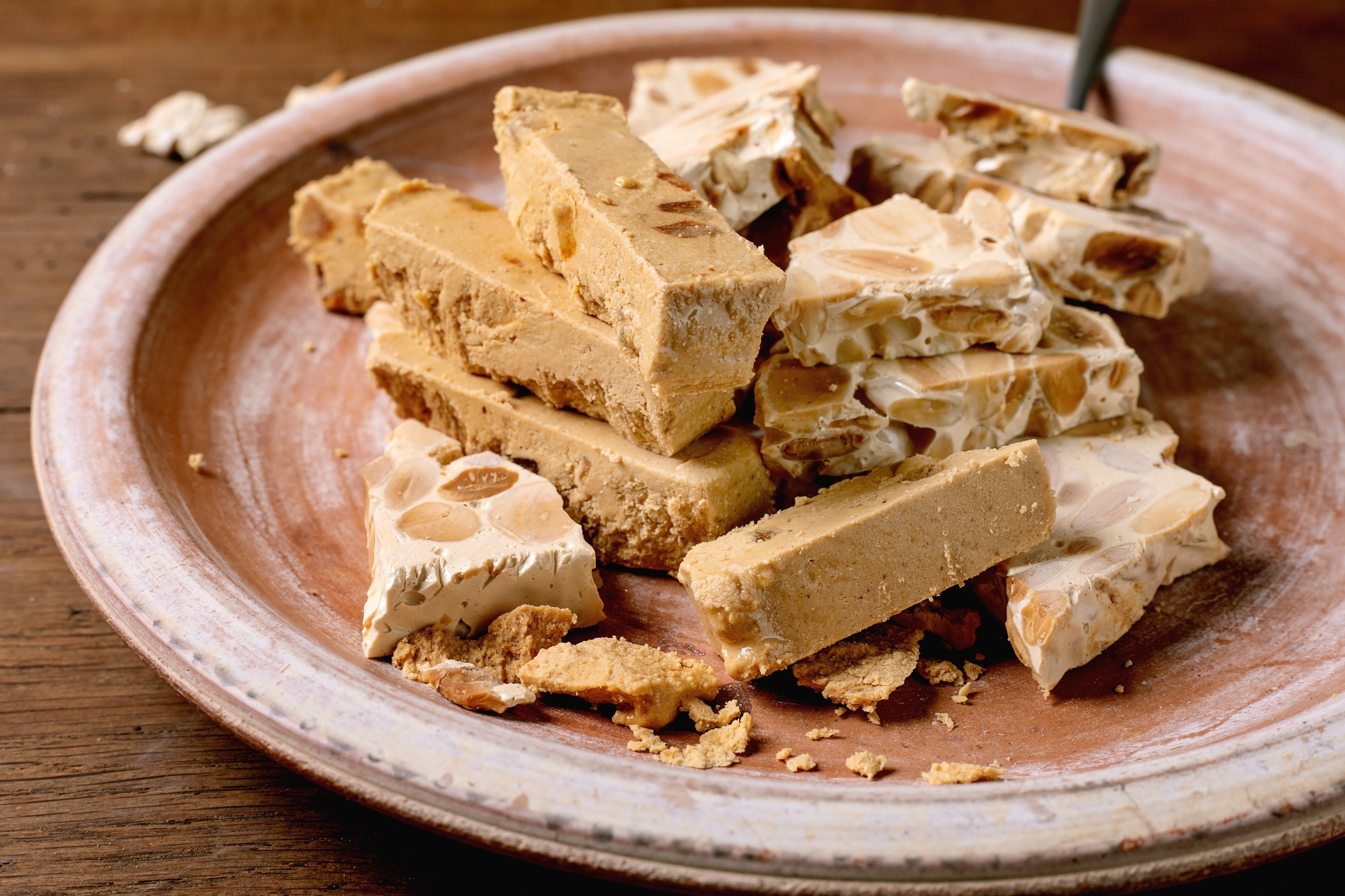 Spansk turron med mandler og nougat på rustikt lerfad – traditionel julegodteri fra Spanien