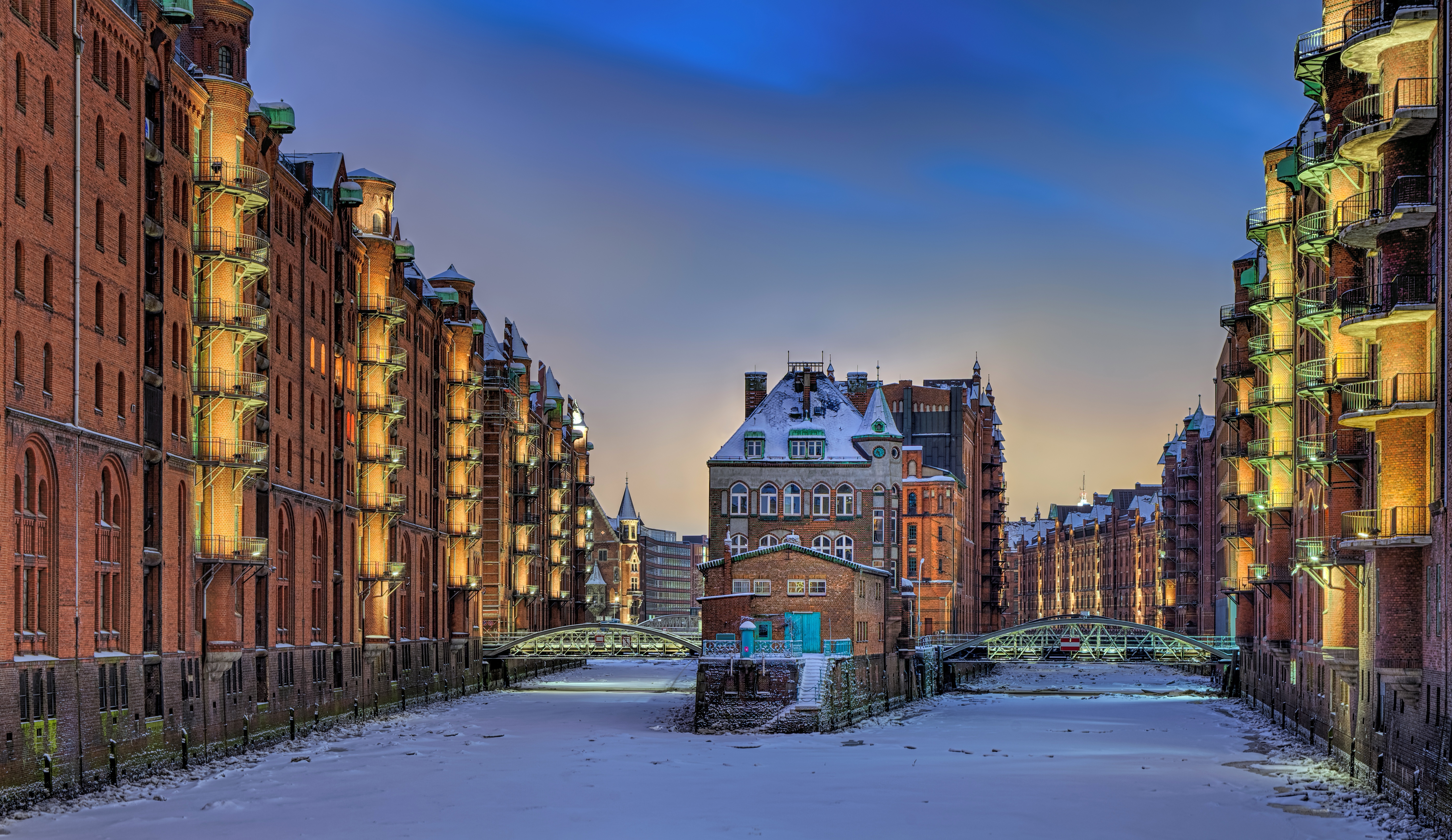 Smuk vinterstämning i Hamburgs Speicherstadt med snebelagte broer, frosne kanaler og varmtbelyste historiske lagerbygninger