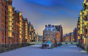 Smuk vinterstämning i Hamburgs Speicherstadt med snebelagte broer, frosne kanaler og varmtbelyste historiske lagerbygninger