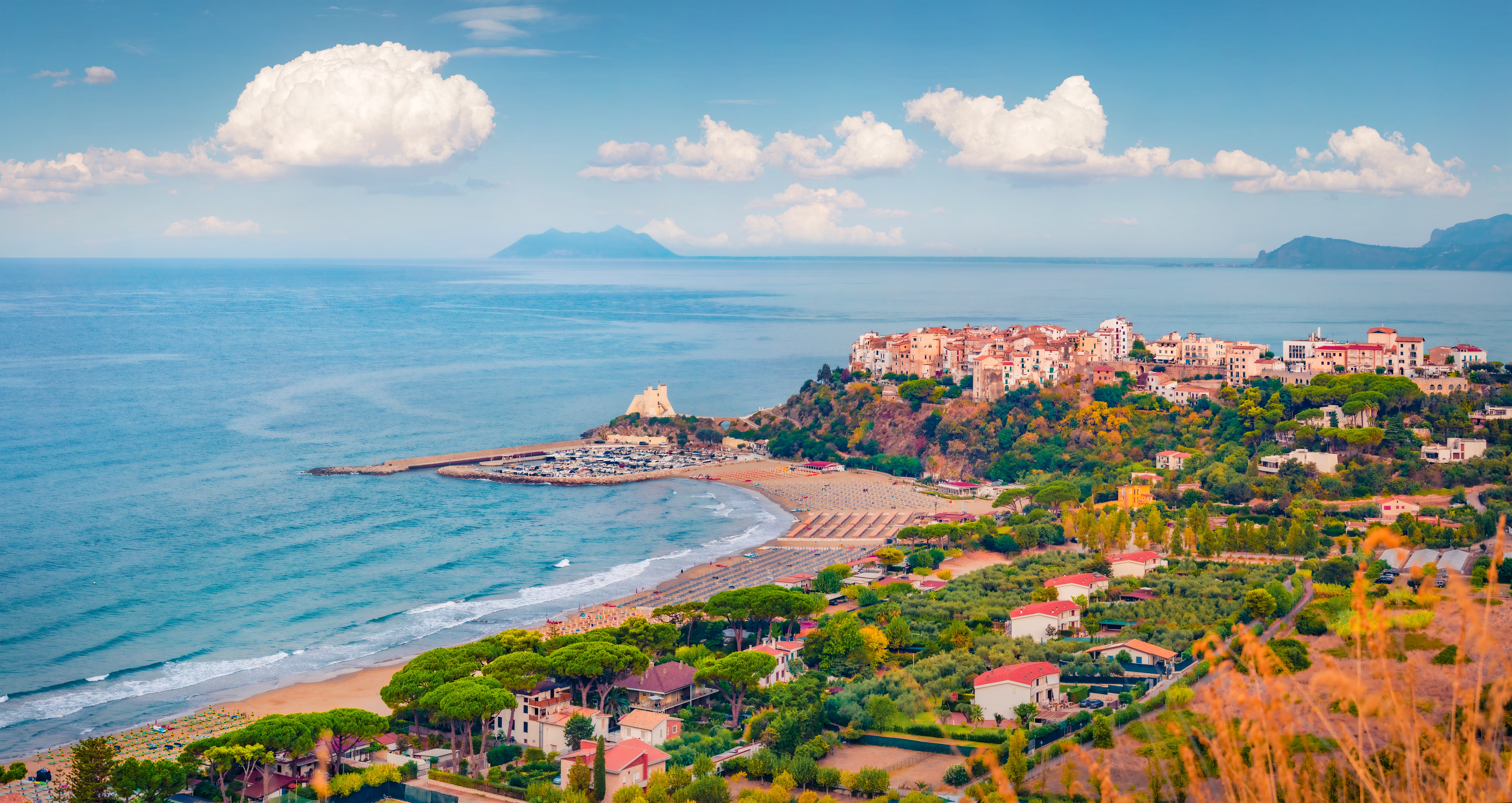 Luftfoto af den idylliske italienske kystby Sperlonga med sandstrand, havn og historisk tårn ved Middelhavet