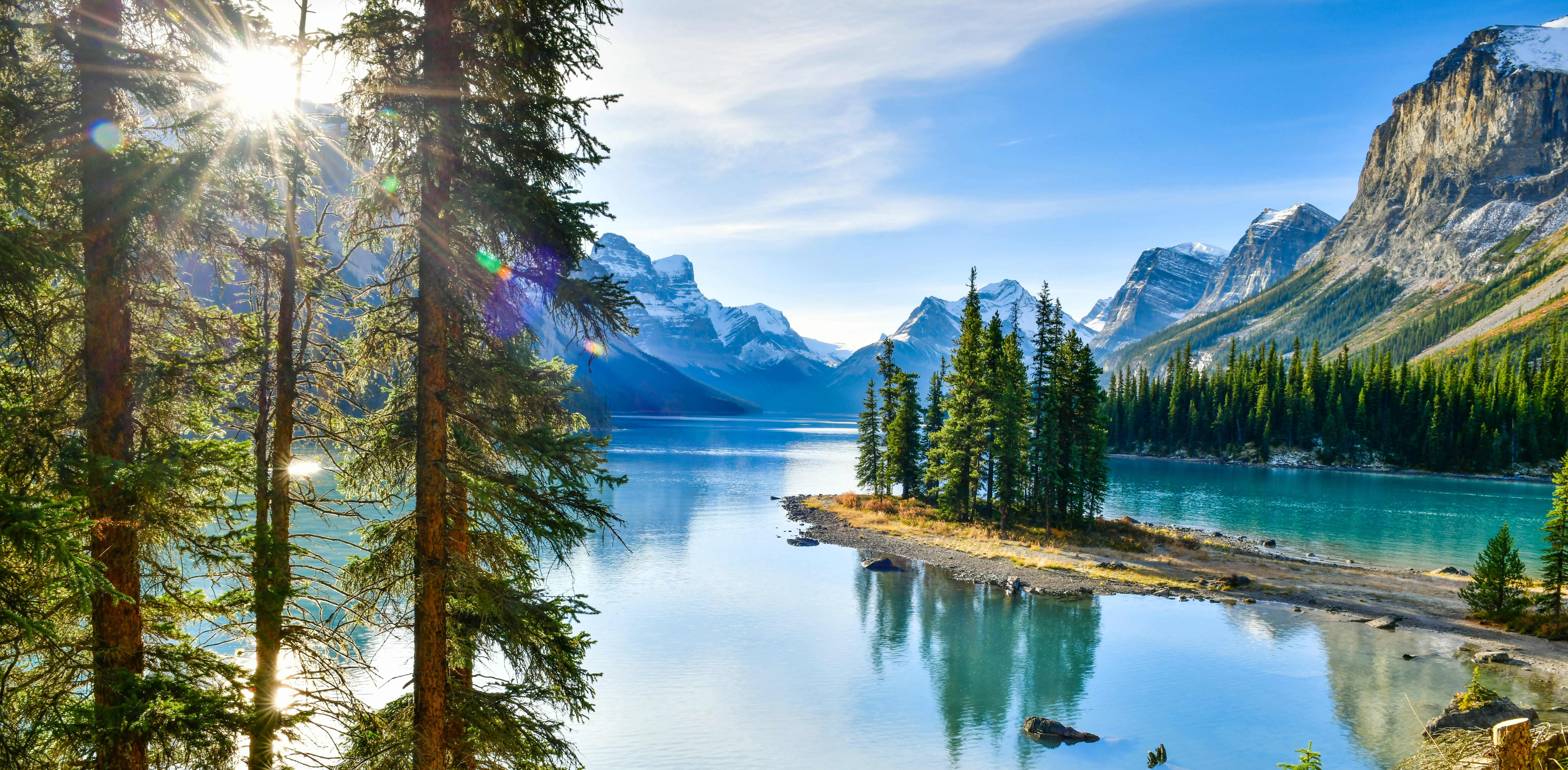 Naturskøn panoramaudsigt over Spirit Island og Maligne Lake omgivet af nåletræer og snedækkede Rocky Mountains i Jasper, Canada