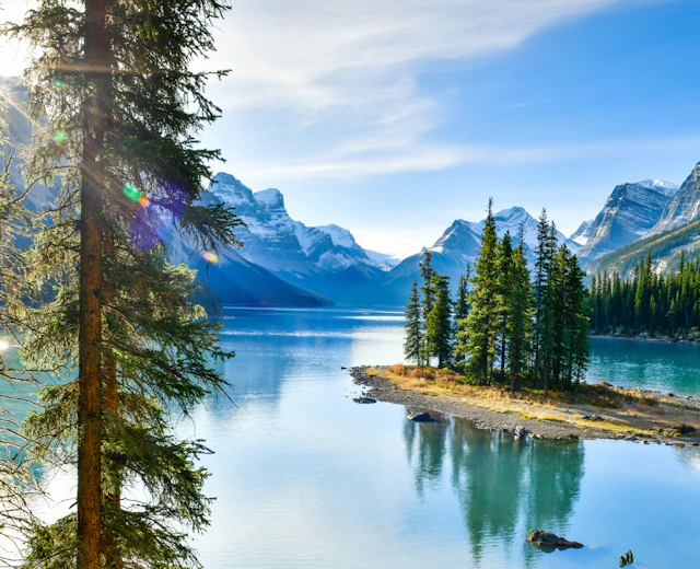 Naturskøn panoramaudsigt over Spirit Island og Maligne Lake omgivet af nåletræer og snedækkede Rocky Mountains i Jasper, Canada